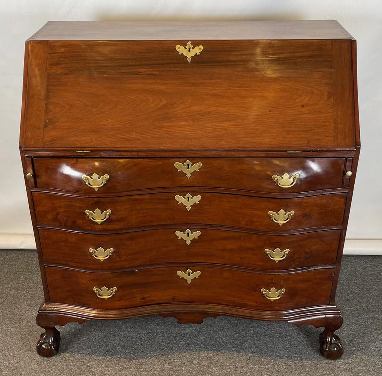 A late 18th C. American mahogany slant-top serpentine front desk; the four graduated drawers resting on short cabriole legs terminating in elaborately carved ball and claw feet.