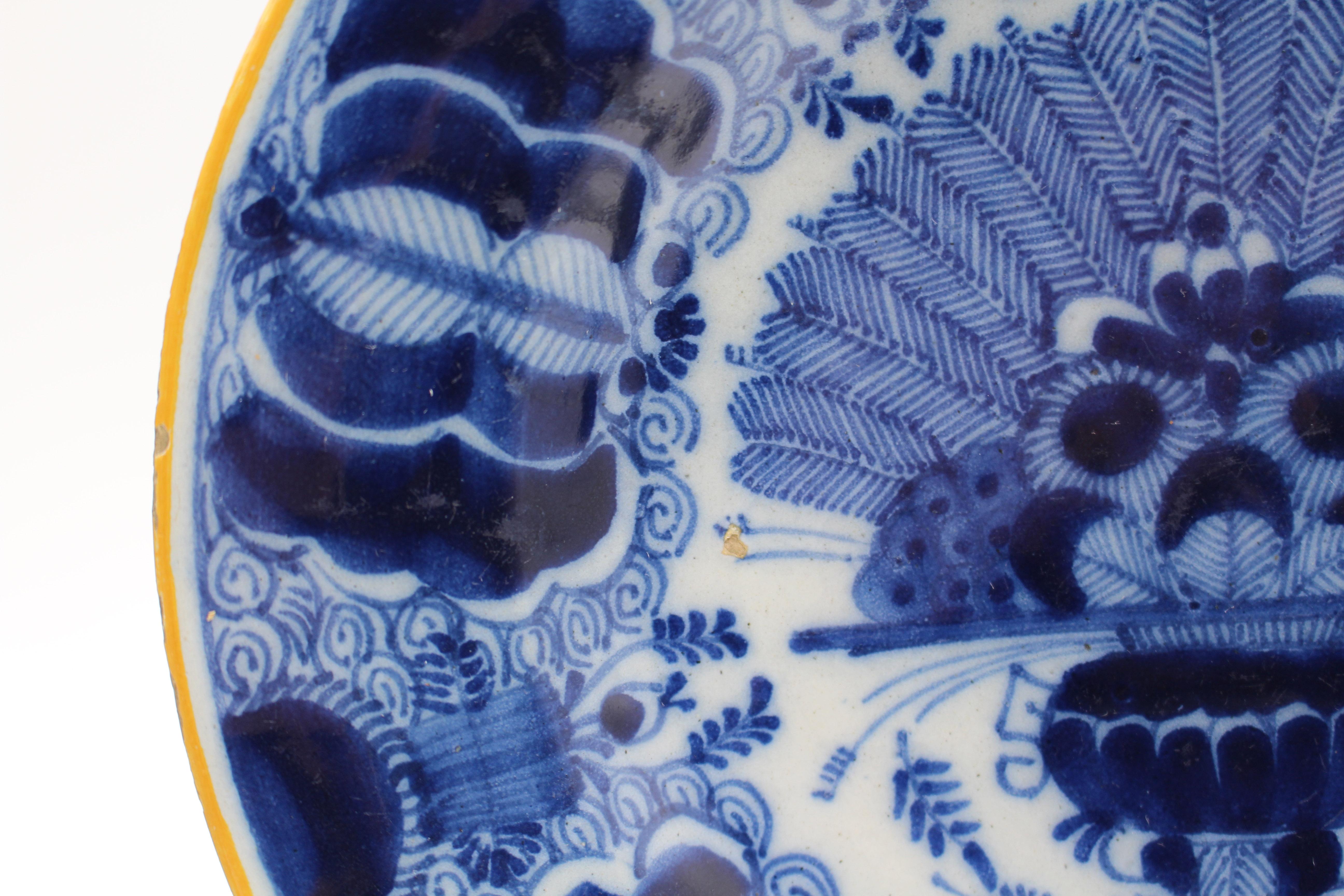 Late 18th century associated pair of Delft blue & white peacock feather plates. Deep blue. Popular central fan of peacock feathers in vase pattern by De Klaauw (The Claw) factory. Yellow rims. Rim frits & minor chips.

9