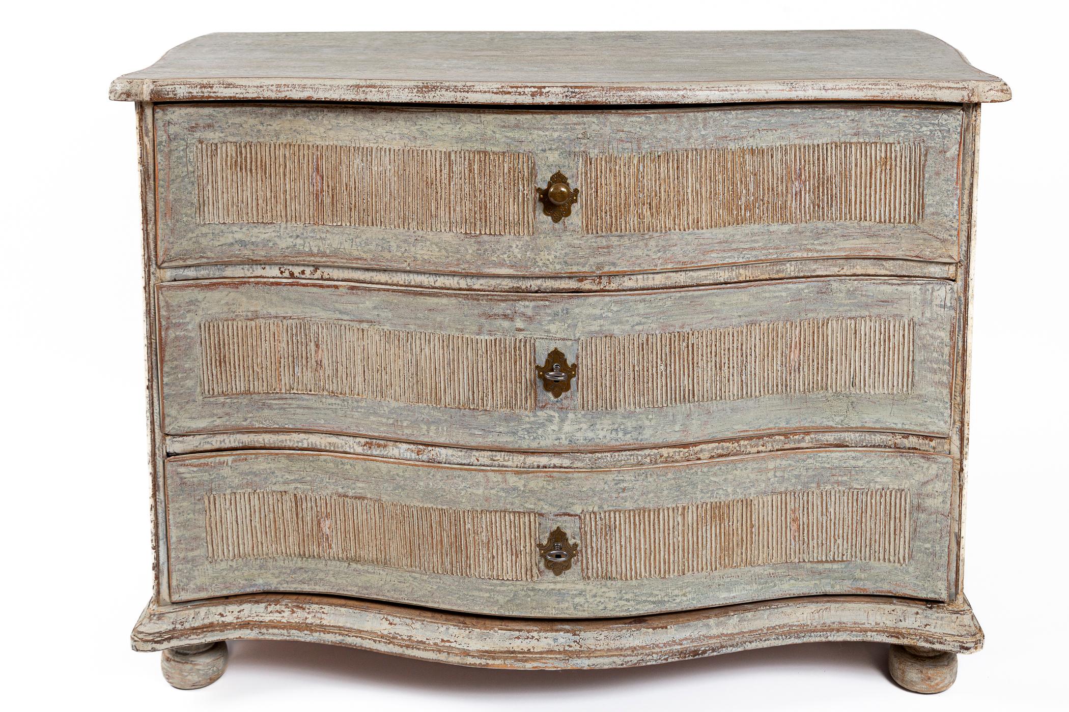 A wonderful serpentine fronted three drawer chest with minimal detaling but lovely carved reeded inst panels and deep moulding trim base and plateau and finishing on bun feet. Note beautiful brass escutcheons with the top drawer offering a knob