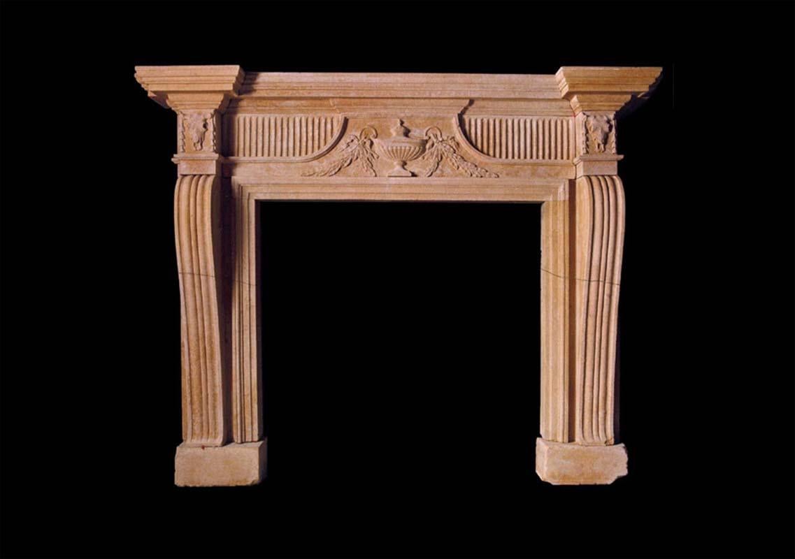 A very handsome late 18th c. Bathstone chimneypiece with console jambs and fluted frieze panels flanking a center tablet carved with a fruiting urn. The corner blocks with Bucranium masks.