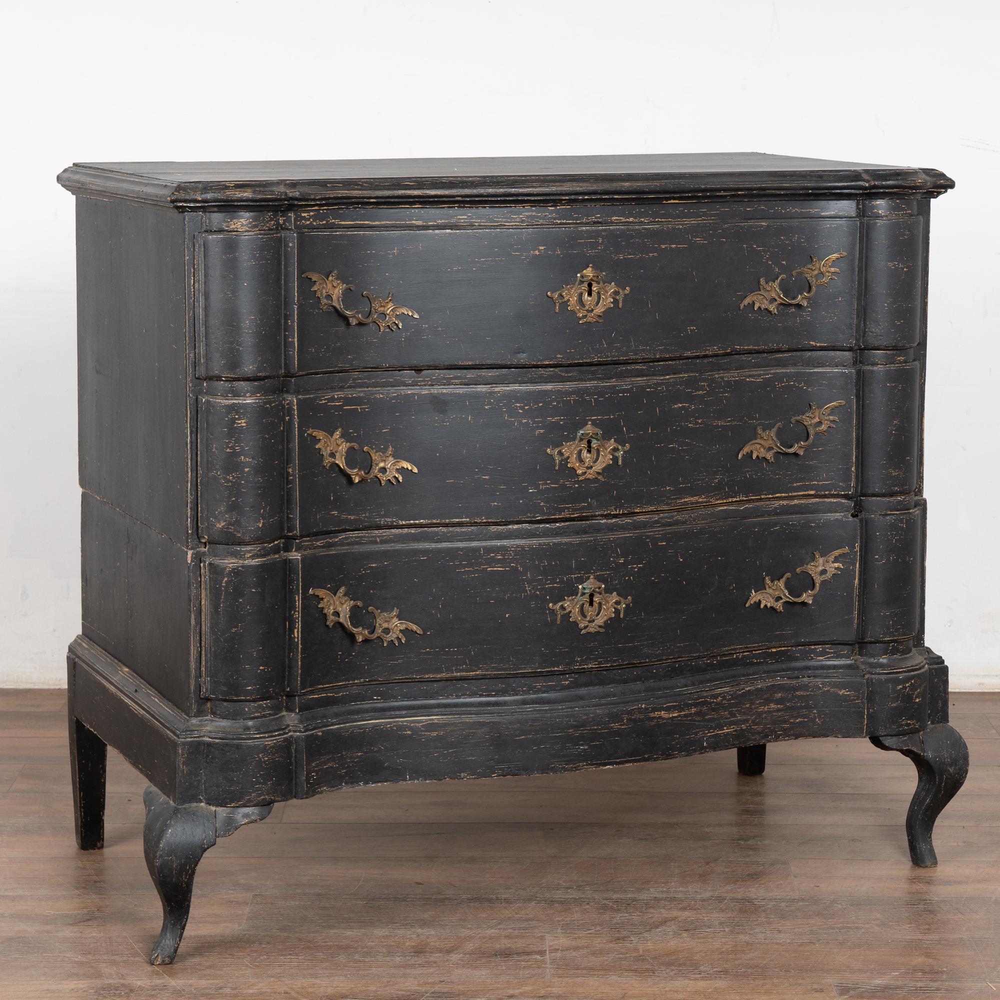 The black painted finish is striking in this oak chest of three drawers resting on curved cabriole front feet.
The newly applied black painted finish is distressed throughout, revealing natural wood below while complimenting the age and serpentine