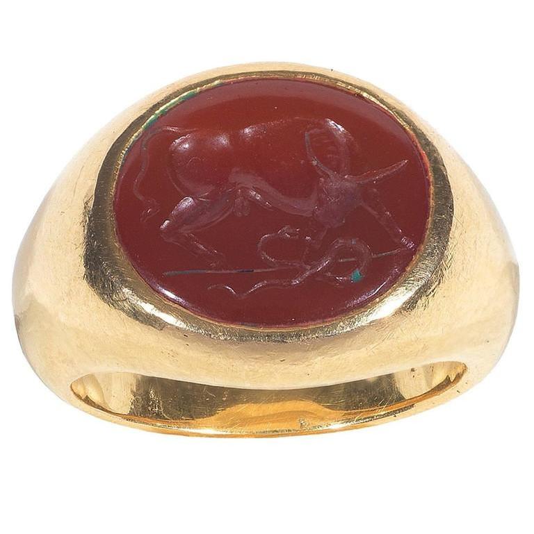
The oval carnelian depicting a standing bull fighting against a snake.

Carnelian size: 15 x 13 mm

Mounted in 18Kt yellow gold chevalier shape ring

Weight: 19.7 gr

Finger size: 8 3/4

In the Christian iconography the bull has been seen as a