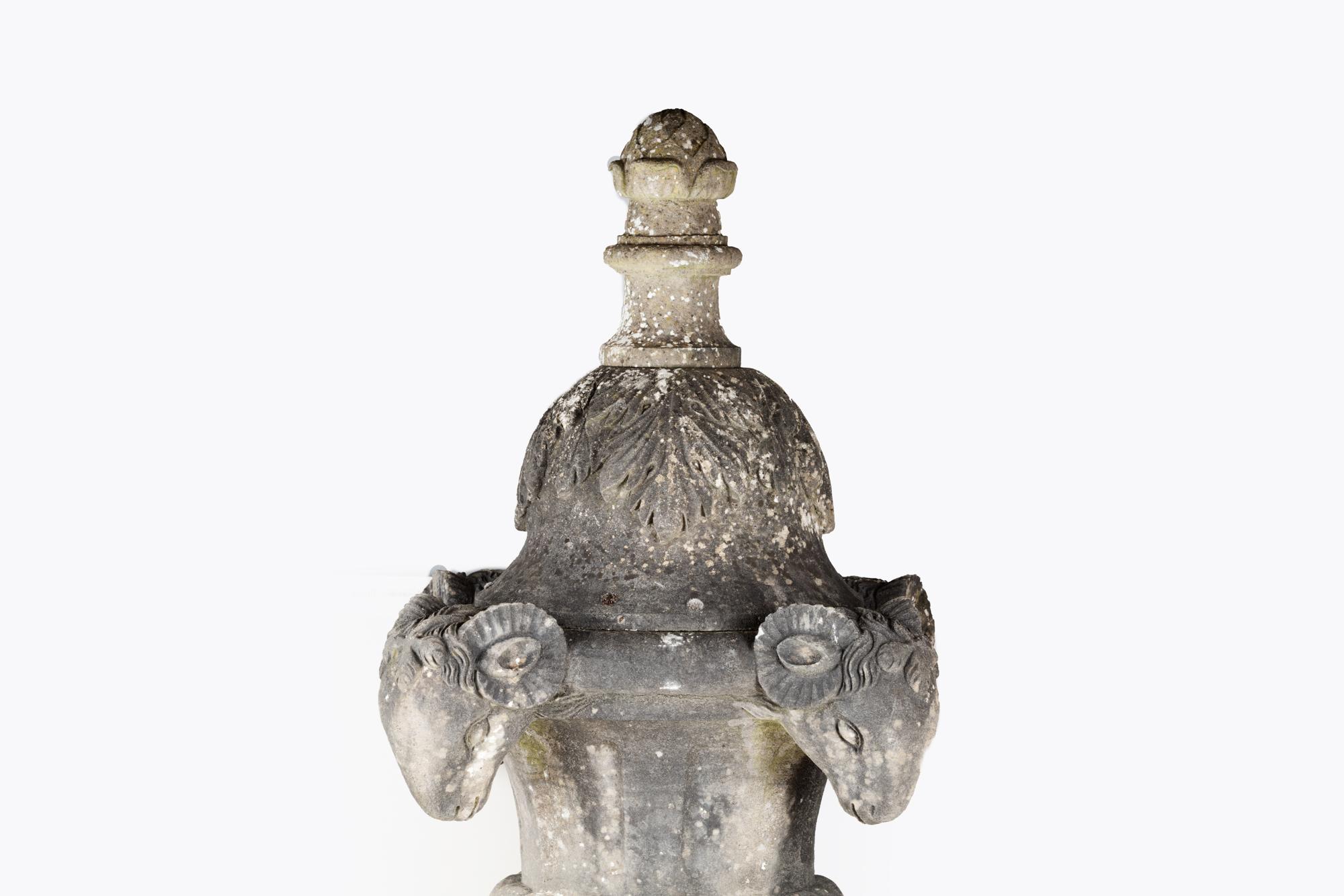 Late 18th century campana shaped carved limestone garden urn with stylised ram heads.
This piece features a refined Classic decoration with acanthus leaf motifs applied to the lid and is flanked by four large ram heads to the rim. The bowl is