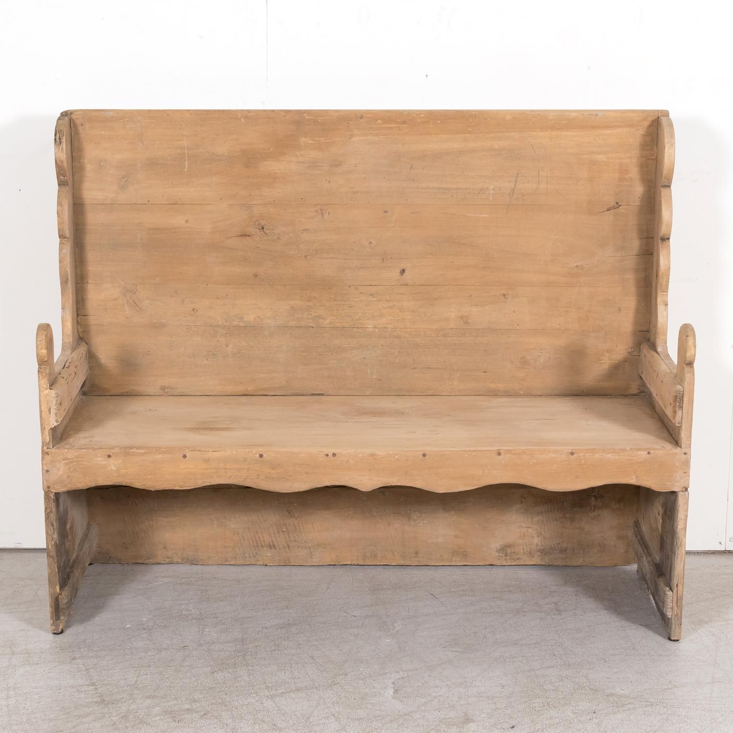 A late 18th century primitive settle bench handcrafted in the Catalan region of Spain of mélèze, a hard pine grown in mountainous regions, circa 1790s. Having a carved scalloped wing back and scalloped apron, this handsome Spanish bench features