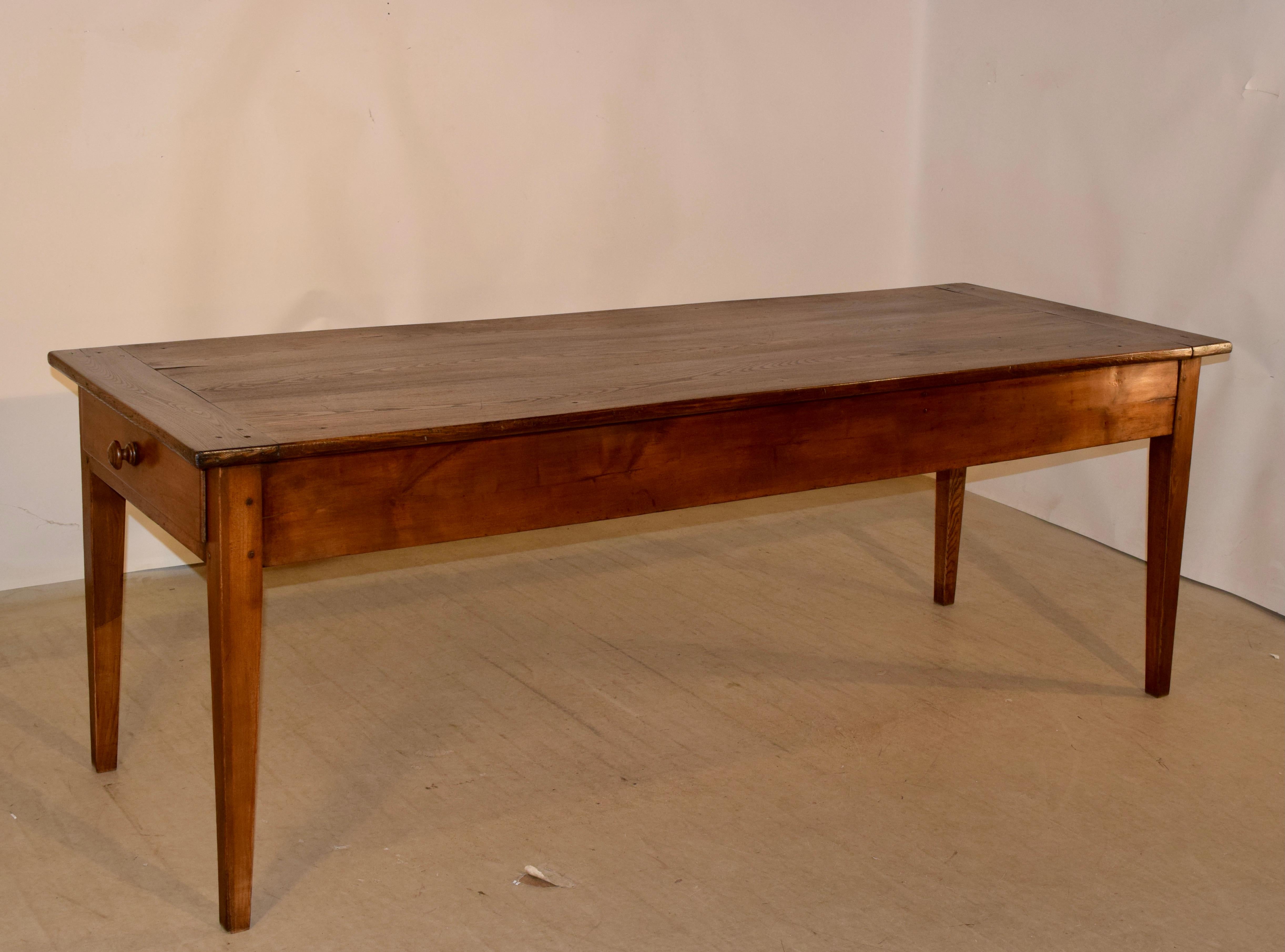 18th century chestnut farm table from France with a three board top which has banded ends, following down to a simple apron, measuring 24 inches in height. The apron contains three drawers, one on each end and a smaller one in the front of the
