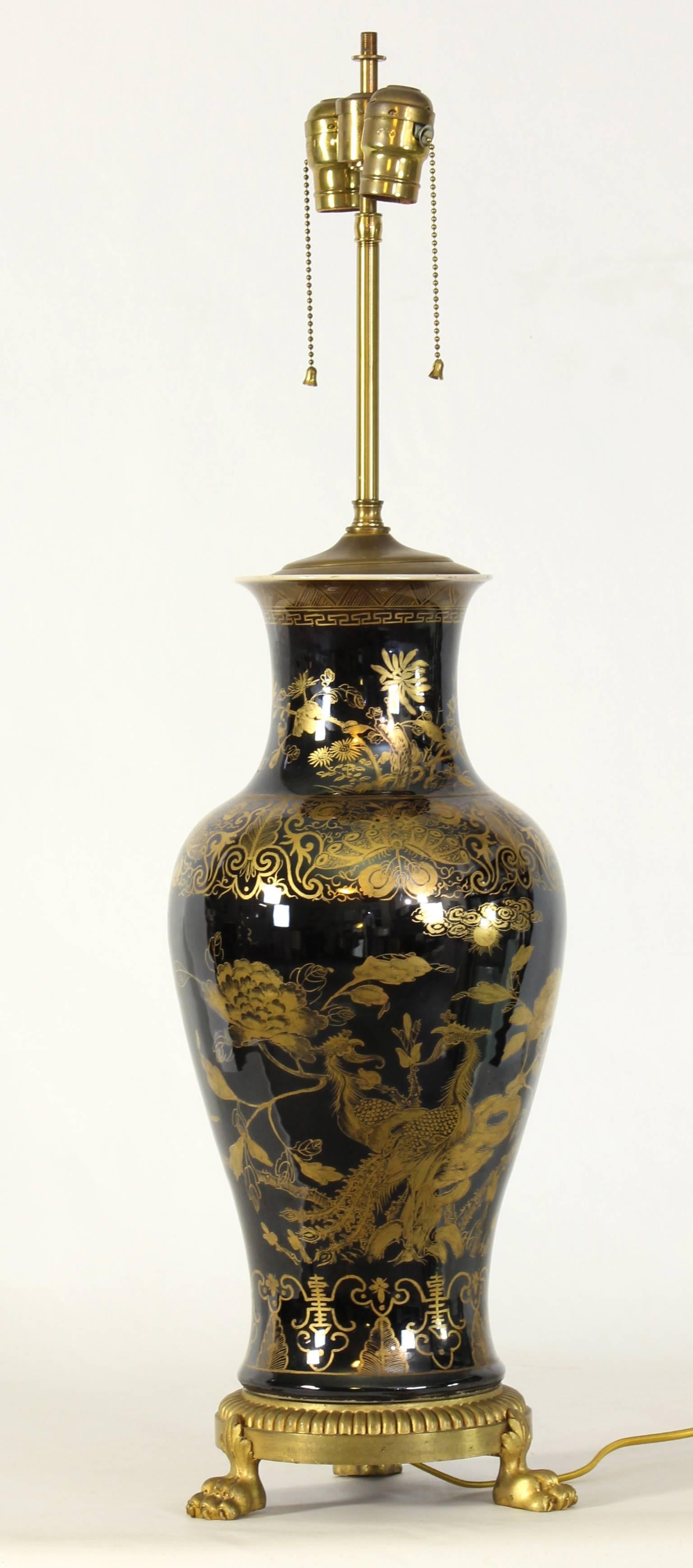 A very rare, large and intricately decorated Chinese Export mirror Noir balustrade shaped vase on a gilt bronze base fashioned into a lamp in the early part of the 20th century.