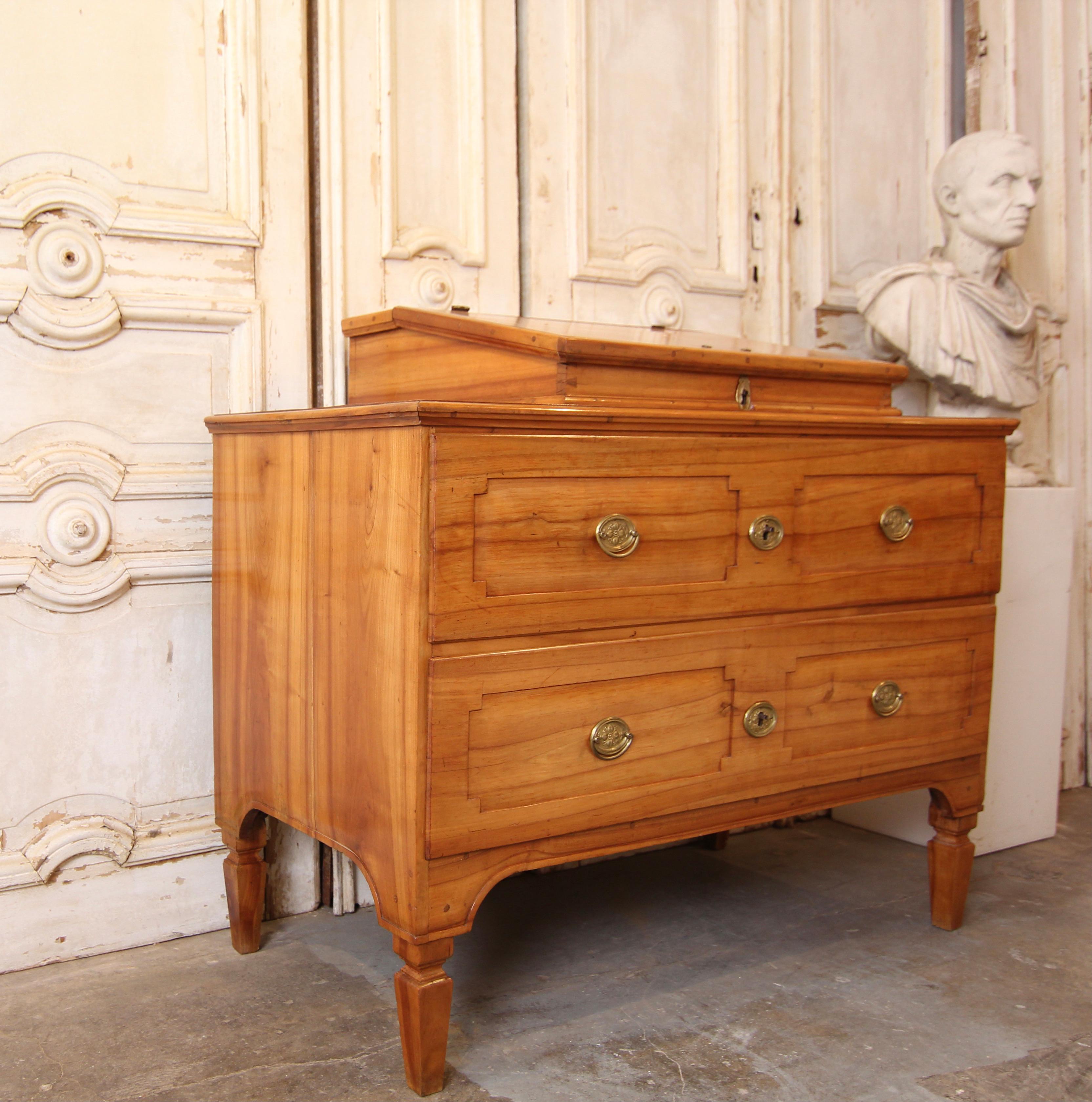 Classicist chest of drawers with desk. Southern Germany/Austria, around 1790. Solidly made of cherry wood.

Rectangular corpus with 2 drawers and slightly overhanging profiled top standing on conical square legs. Fixed desk top with 3 small