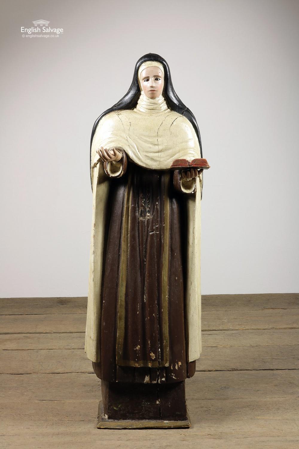 Reclaimed late 18th century wooden statue, reputedly from Spain. Hand carved and painted, depicting either a female saint or a nun, with inset glass eyes, with outstretched arms, holding a book.

Splits, small chips and dings.