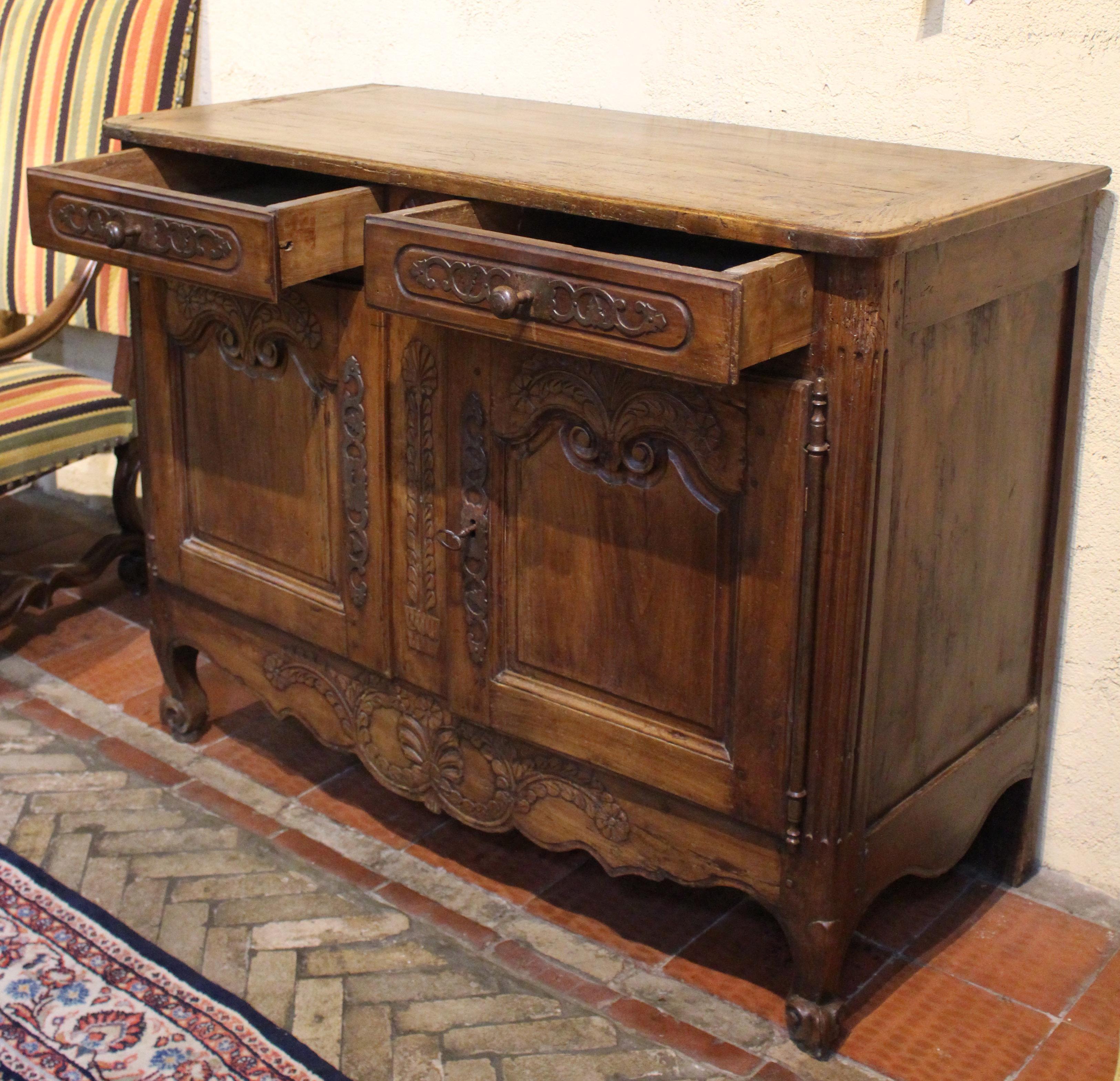 Late 18th century country French buffet. Original steel hardware & escutcheons. Cherry & poplar. Two drawers over two doors. Well carved throughout the front with bold sprays of leaves ending in florets, rosette between the drawers and well shaped