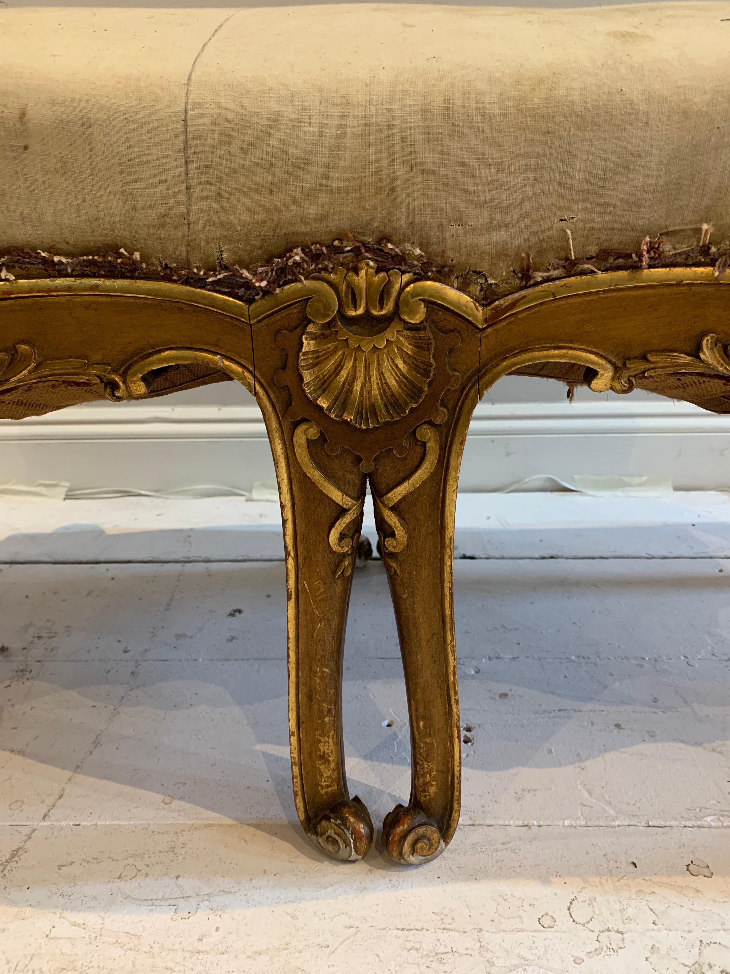 A substantial late 18th century gilt wood window seat/bench from an Irish country house. Inspired by the French rococo-style which is characterised by its lavish and high-relief carvings. 
The seat features high sides, carved swags, shells and