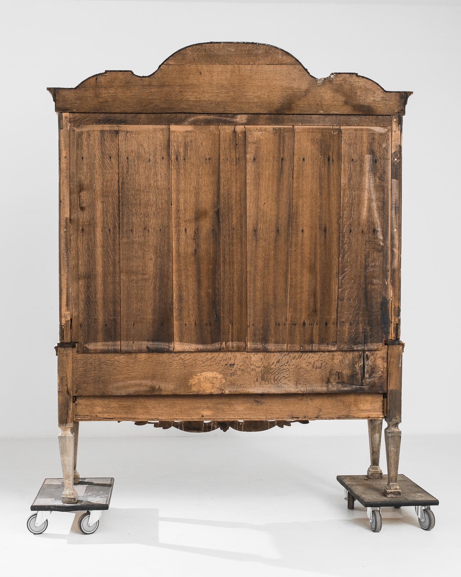 A bleached oak ‘kast’ from The Netherlands, produced circa 1780. A grand antique cabinet featuring an ornate crest over a double door cabinet holding three shelves and five interior drawers, a traditional future of Dutch buffets. Three more drawers