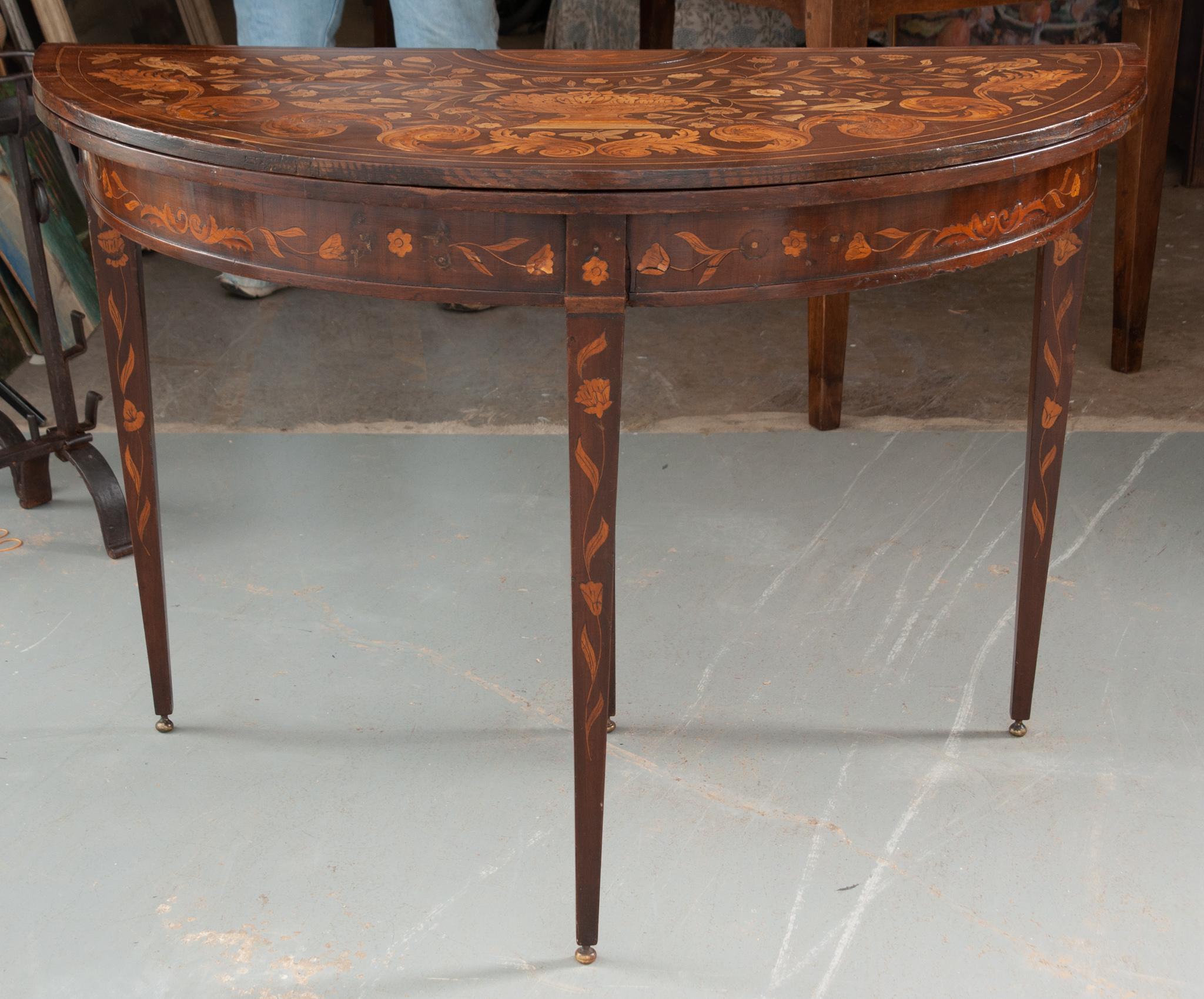 This Dutch game table/ console is made of mahogany with impressive satinwood marquetry, circa 1795. When in demi-lune form the beautiful marquetry motif of flowers, overflowing vase, swallows, and scrolling leaves is on full display. The detailed