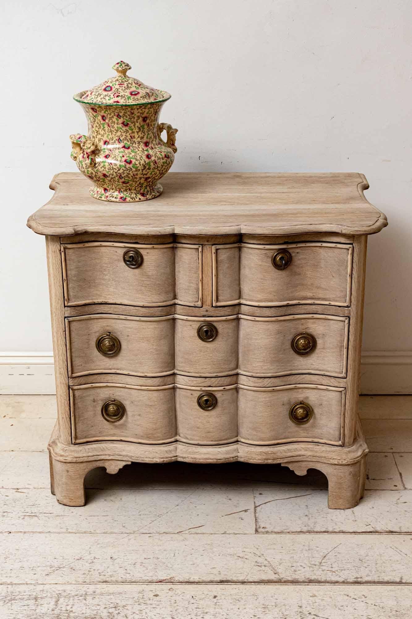 Late 18th century Dutch oak commode or chest of drawers which has been bleached and features an undulating front. Two short drawers sit at the top, each one with a brass key handle (with no locks), with two long drawers beneath each with two brass