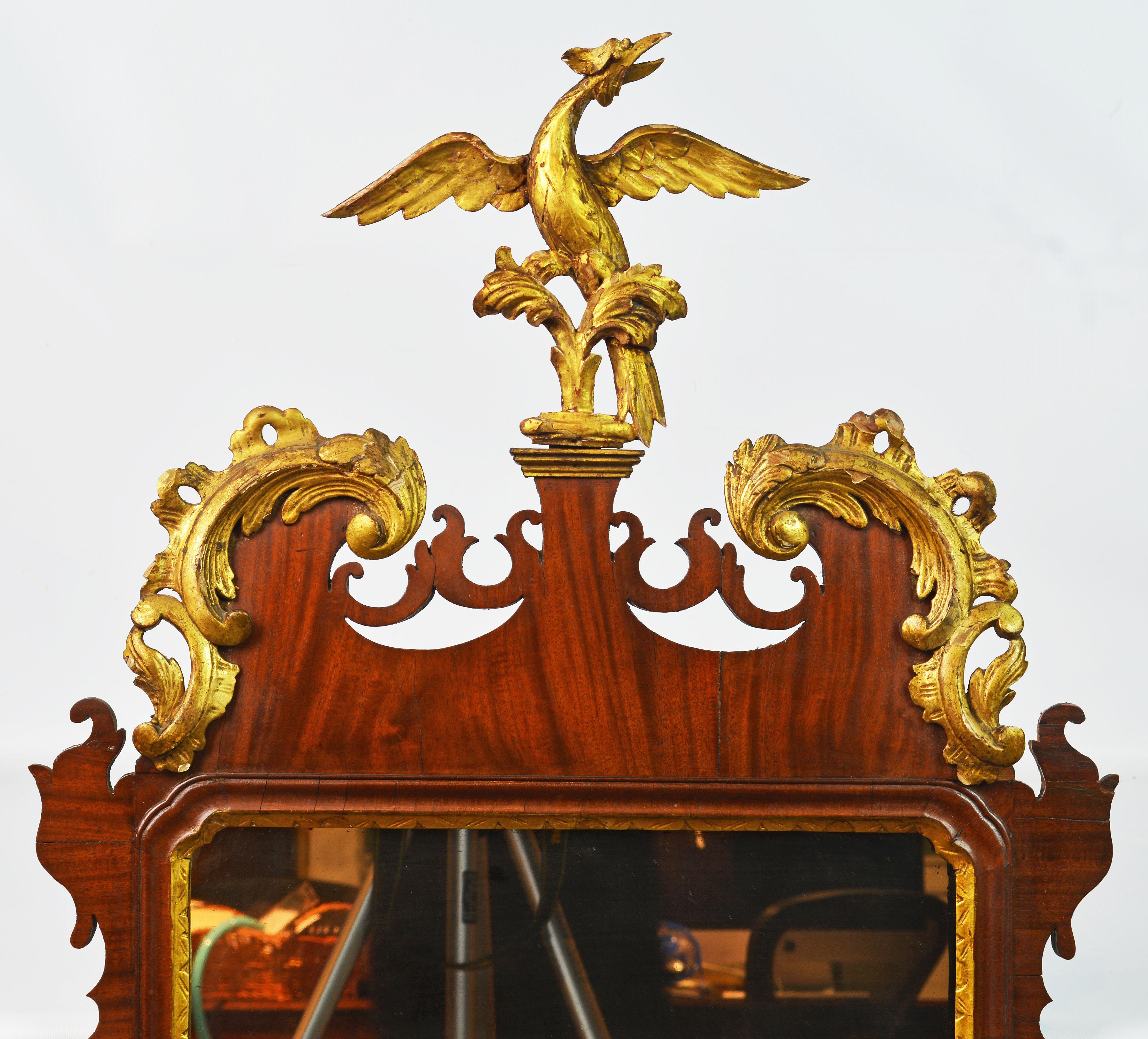 This fine mahogany Chippendale mirror dating to the late 18th century features a pediment with elaborate gilt foliate scrolls centering a carved gilt phoenix bird above sides with carved gilt leaf garlands and a shaped bottom part. We have judged