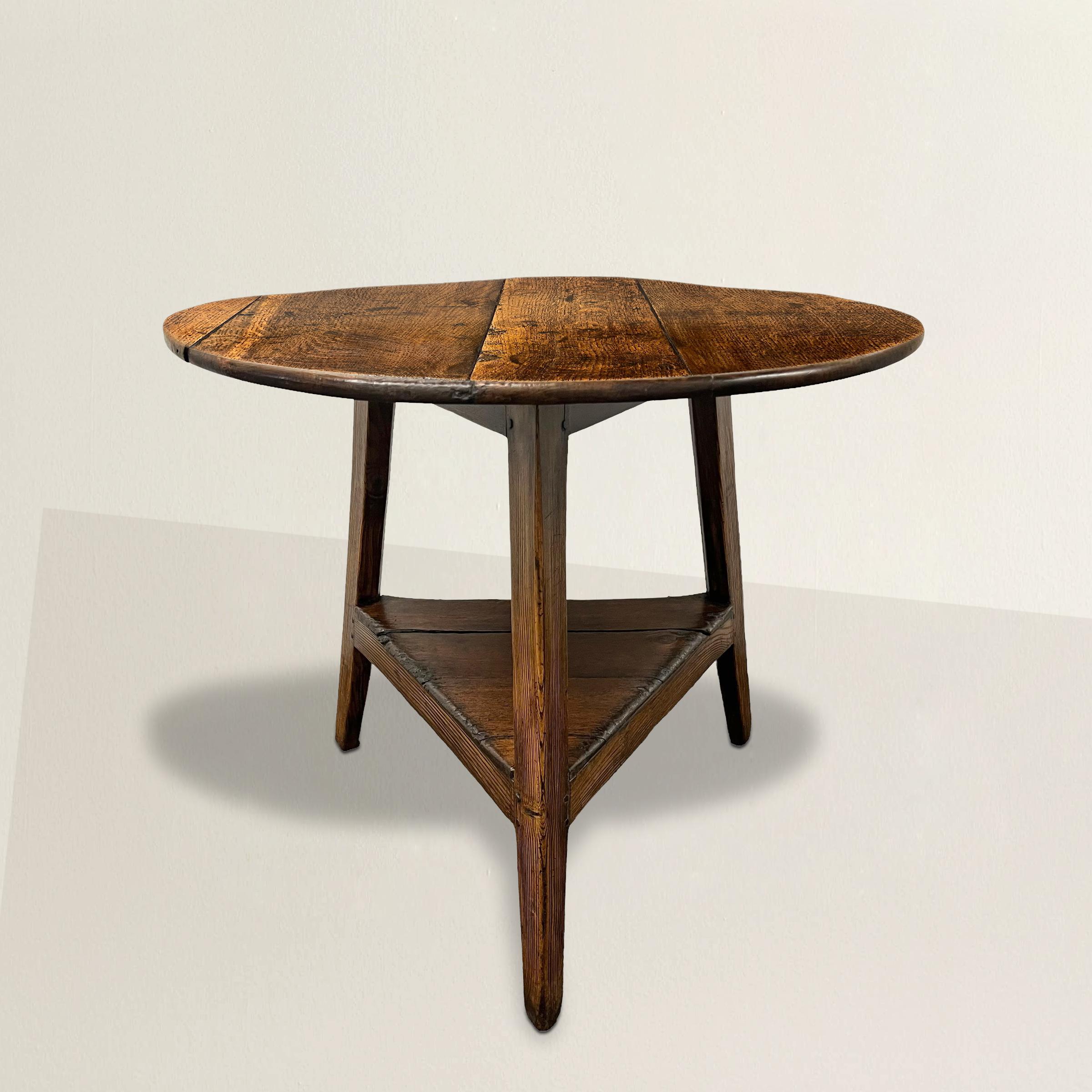 Standing as a testament to 18th-century English craftsmanship, this exceptional elmwood cricket table is a captivating piece of furniture. Its round top boasts a patina that tells the tale of years gone by. Supported by three elegantly tapered legs,