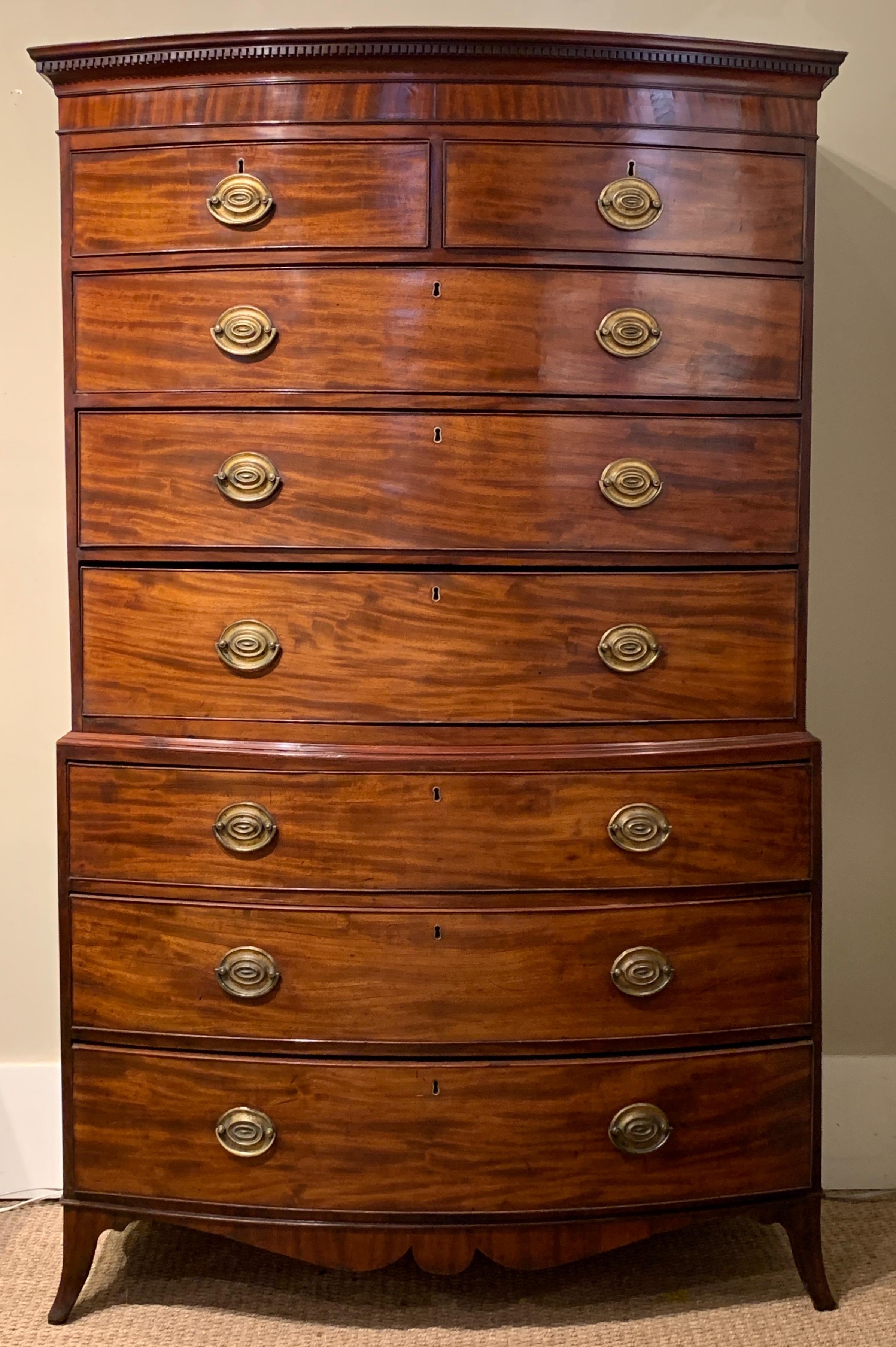 An elegant late 18th century English mahogany bowfront chest on chest. The top portion contains two small drawers over three graduated large drawers and the bottom portion contains three graduated large drawers. The piece is topped with a crown