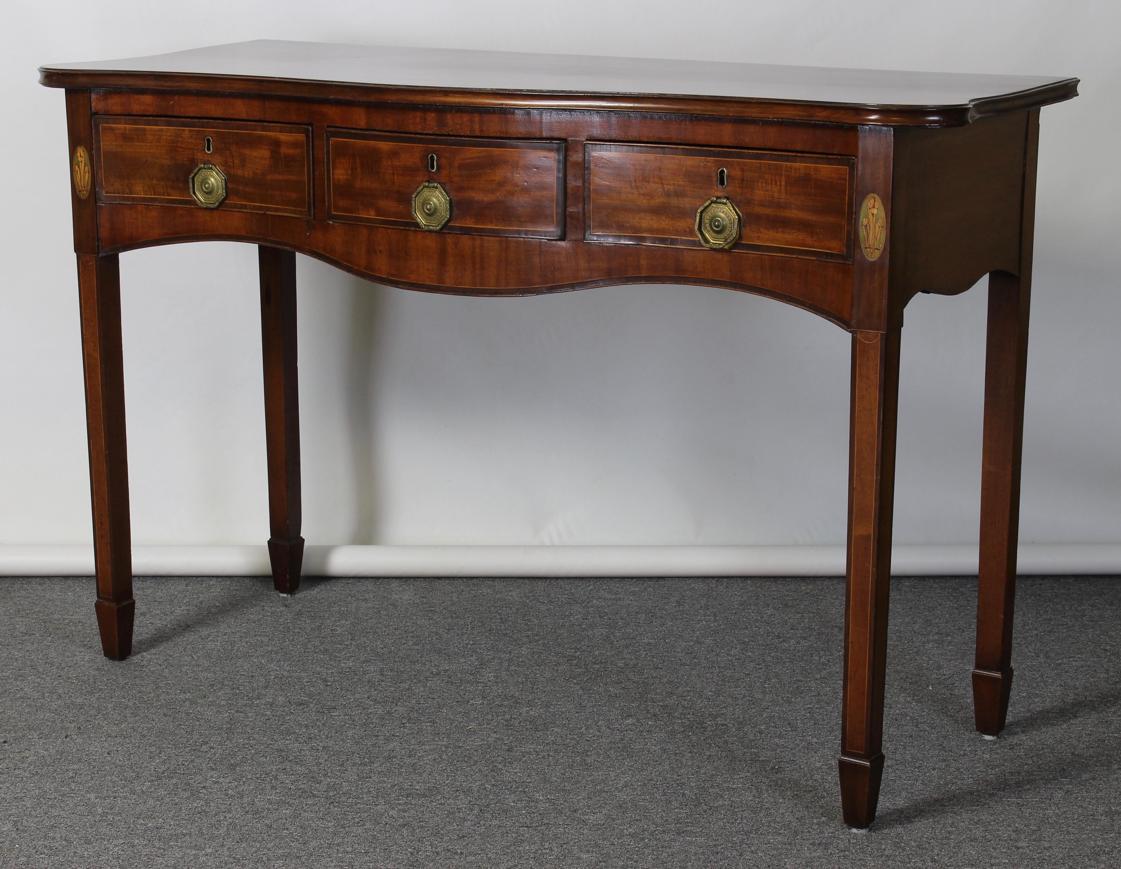 An elegant English George III mahogany serpentine top console table accented with intricate shell inlay and original pulls resting on Marlborough legs.