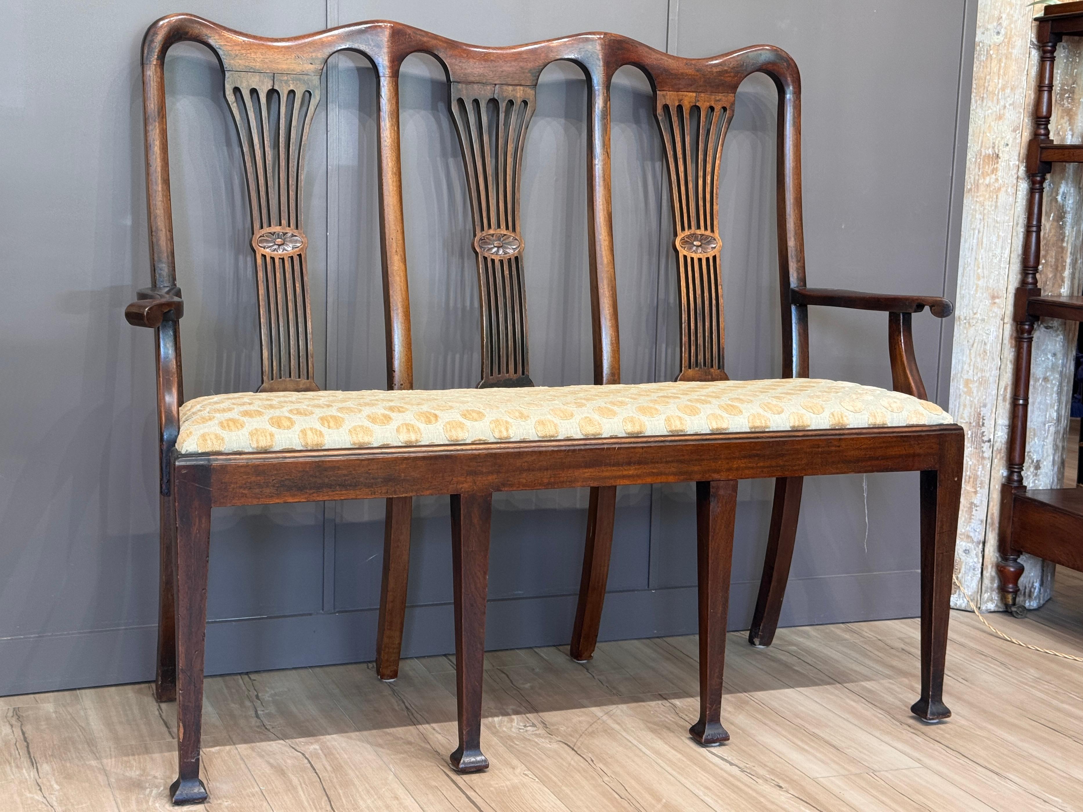 Banc d'entrée en acajou de la fin du XVIIIe siècle, de style George III, à triple dossier avec des cannelures percées en forme de vase et une traverse supérieure en forme. Le banc est soutenu par des pieds coniques carrés se terminant par des pieds