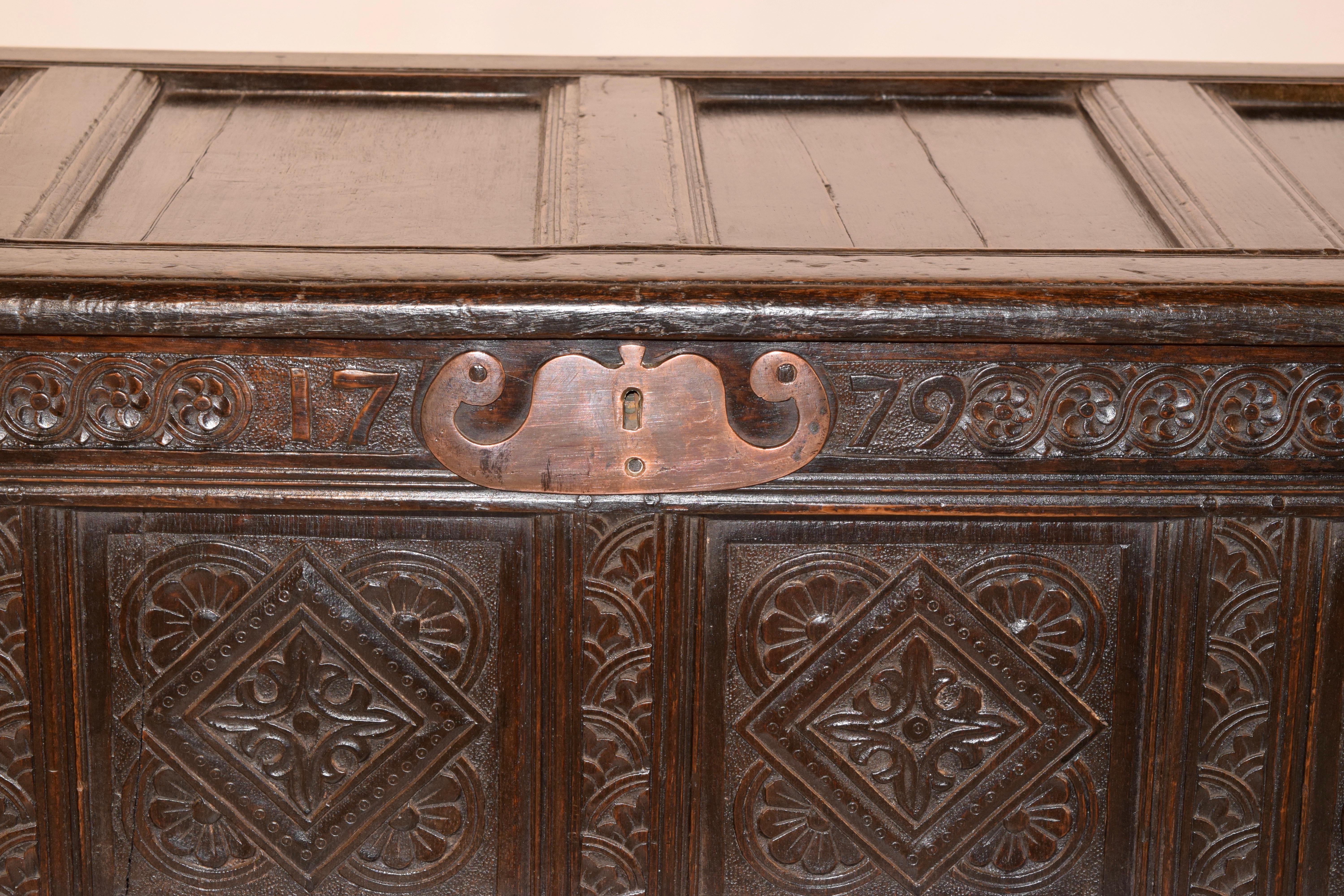 Late 18th century oak blanket chest from England. The chest has a quadruple paneled top with molded edges, which lifts to an open interior. The four front panels are hand carved with relieved floral decoration and geometric carving. The chest has