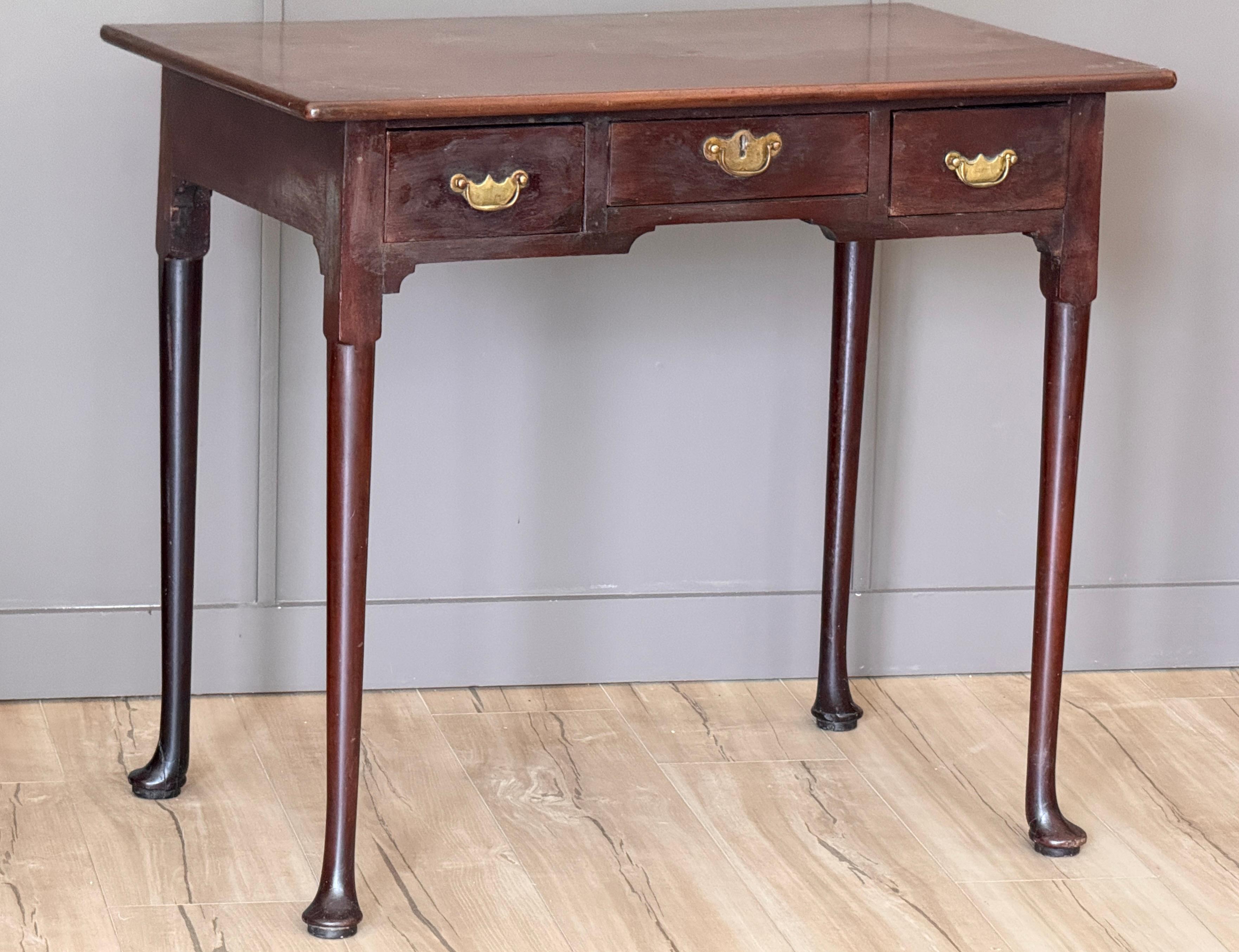 A late 18th C. English three-drawer writing or side table in walnut. The rectangular top sits above a shallow apron fitted with three drawers, raised on elegantly tapered legs terminating in pad feet. Traditional joinery visible in the drawer