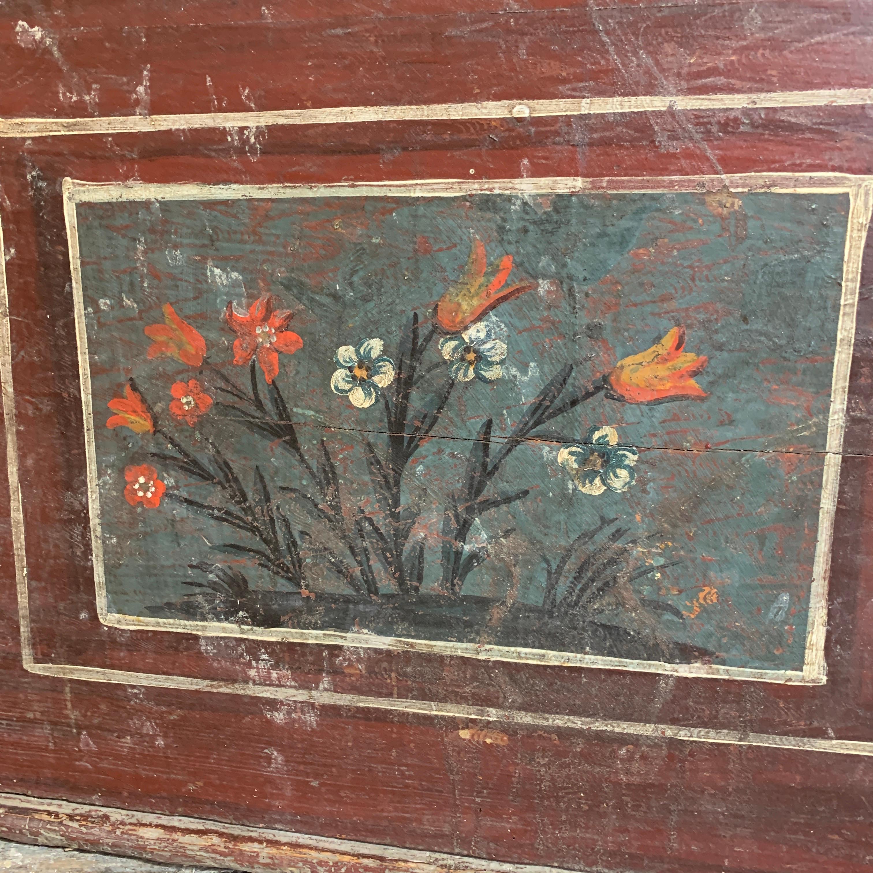 Late 18th century European hand painted marriage chest. The rich dark red base color is highlighted with areas of floral pattern and a heart detail below the lock on the front. Inside the trunk there is a main section plus a small lidded box shelf