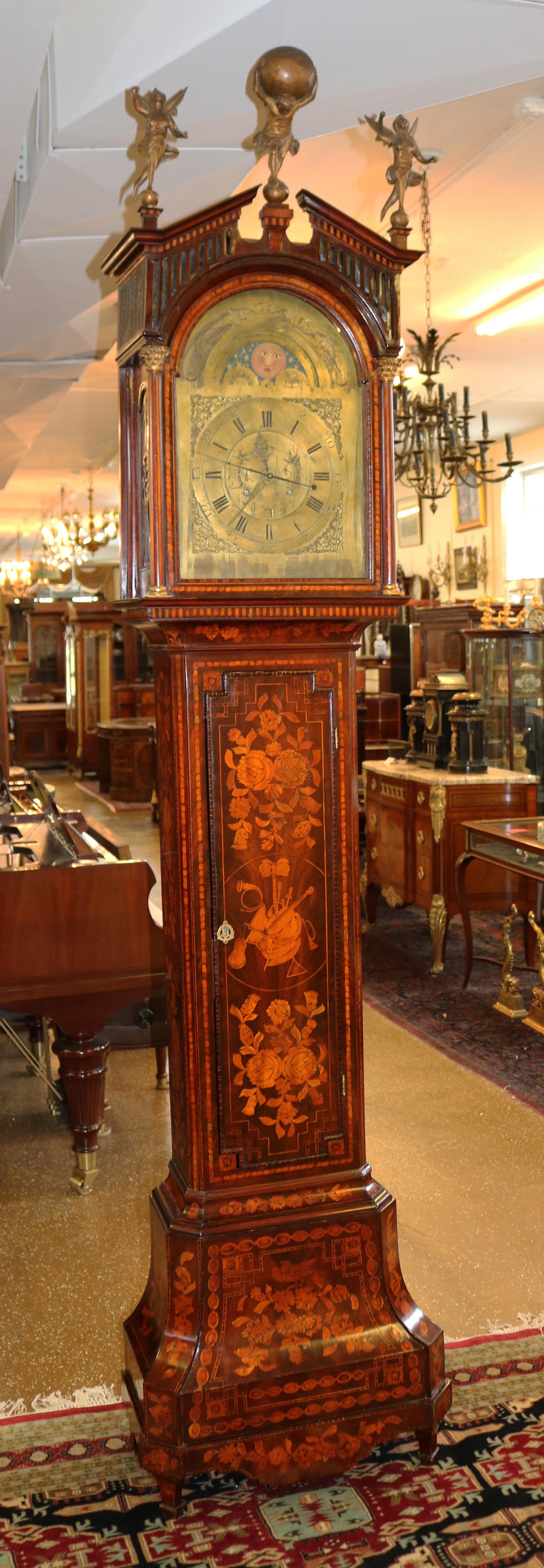 Cette étonnante horloge à boîtier haut a été fabriquée aux Pays-Bas à la fin du XVIIIe siècle. L'étui est magnifiquement incrusté et le sommet de la hotte est orné de deux anges de chaque côté et d'une sculpture d'atlas au milieu. Le mouvement est