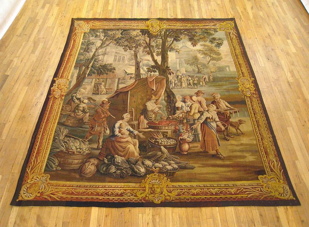 A Flemish rustic tapestry from the late 18th century, featuring a “Vegetable Market” scene in the manner of David Teniers II, with vendors selling various vegetables in the foreground, a man on a soapbox in the background, and a series of quaint