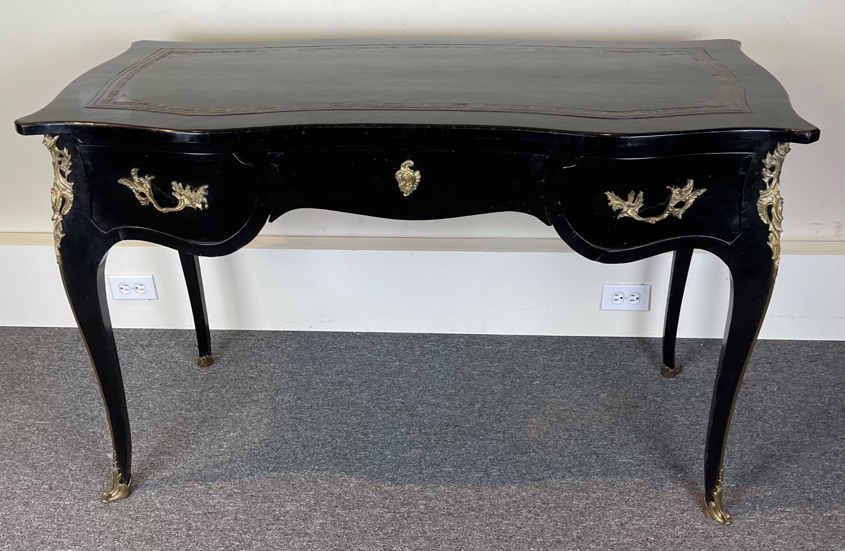 A late 18th C. French Louis XVI ebonized desk with inset tooled leather top above three drawers with cabriole legs accented with gilt bronze mounts.