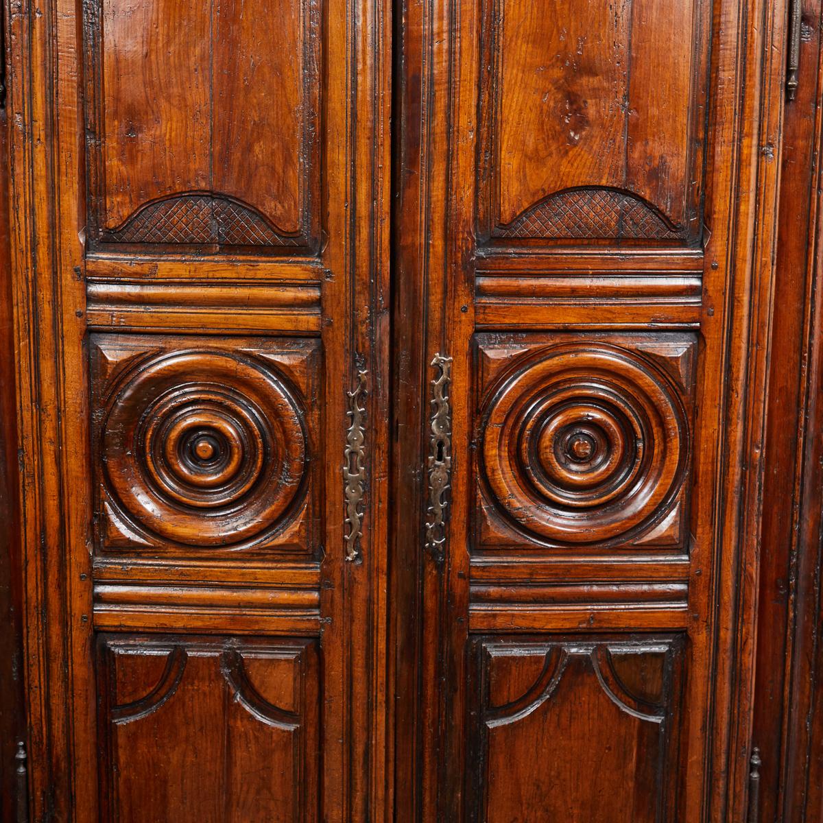 Late 18th century French carved cherrywood armoire. Country armoire with carved panels, roundels, iron hardware, and square feet. Great for storage or as a storage cupboard, comes with lock and key.