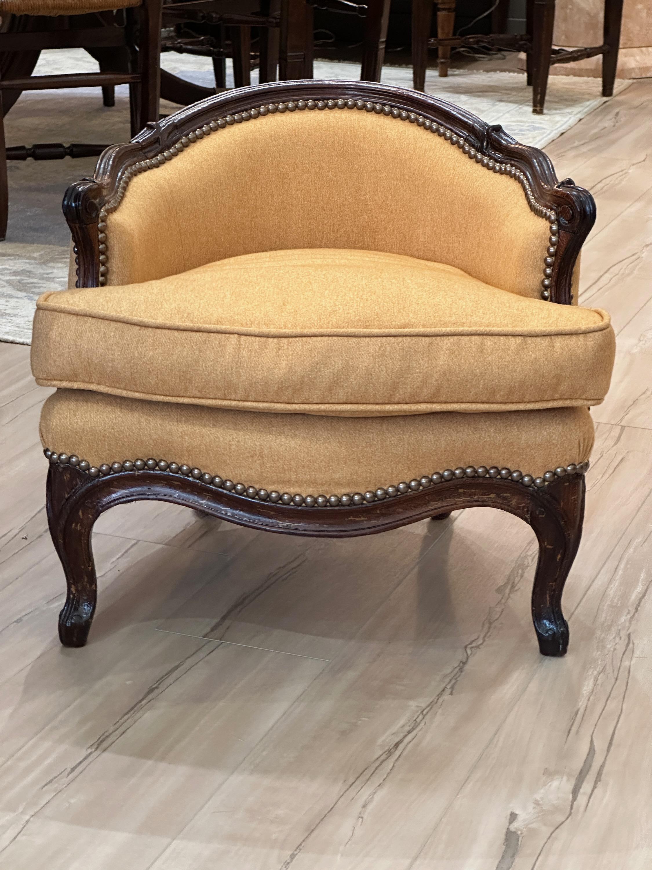 A charming late 18th century. French chauffeuse, or fireside chair, in the Louis XVI style with carved mahogany frame and upholstered in a light apricot colored wool.