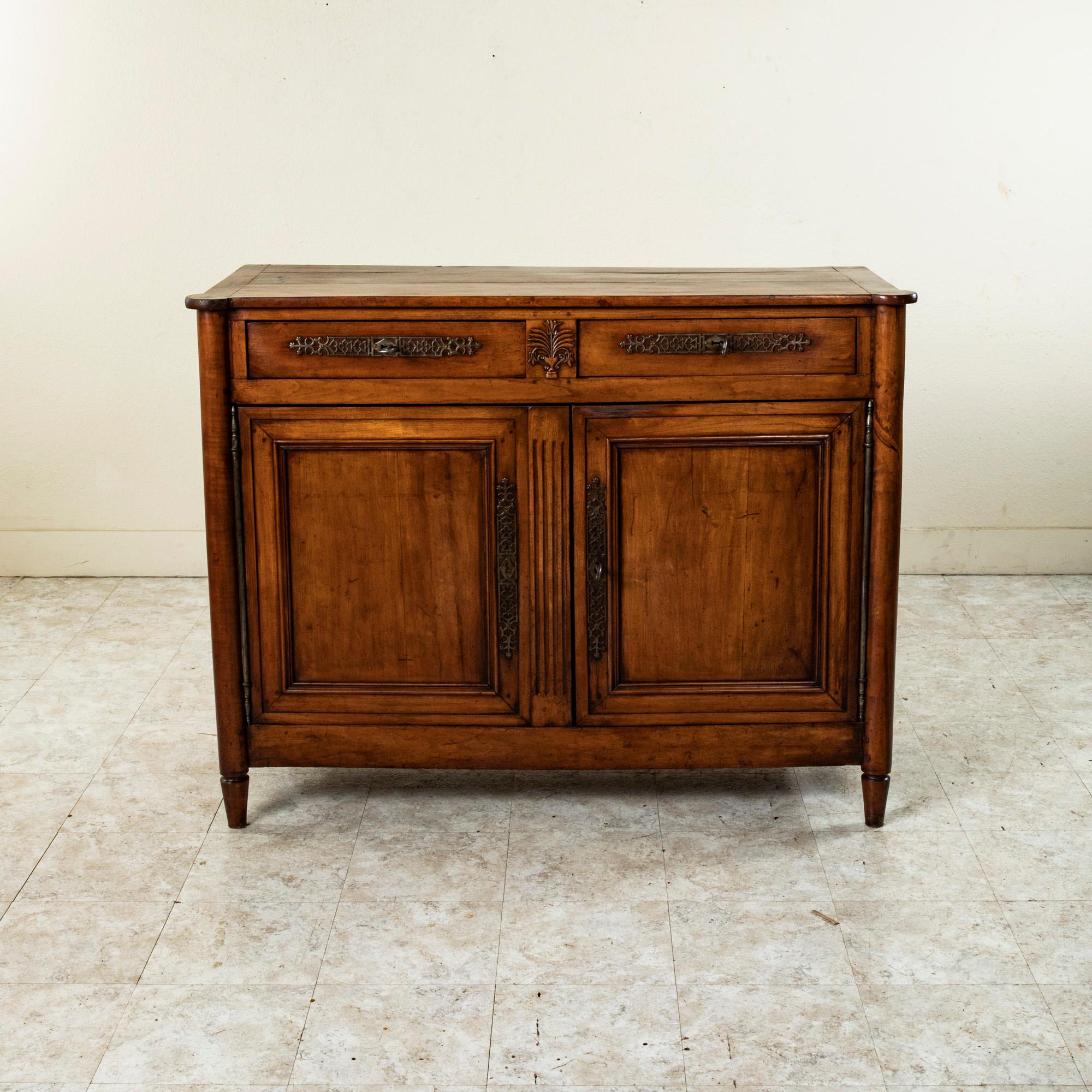 This late eighteenth century French Directoire period cherrywood buffet features its original iron escutcheons with playing card suits of hearts, clubs, diamonds and spades represented. A central hand carved urn with stylized flowers details the