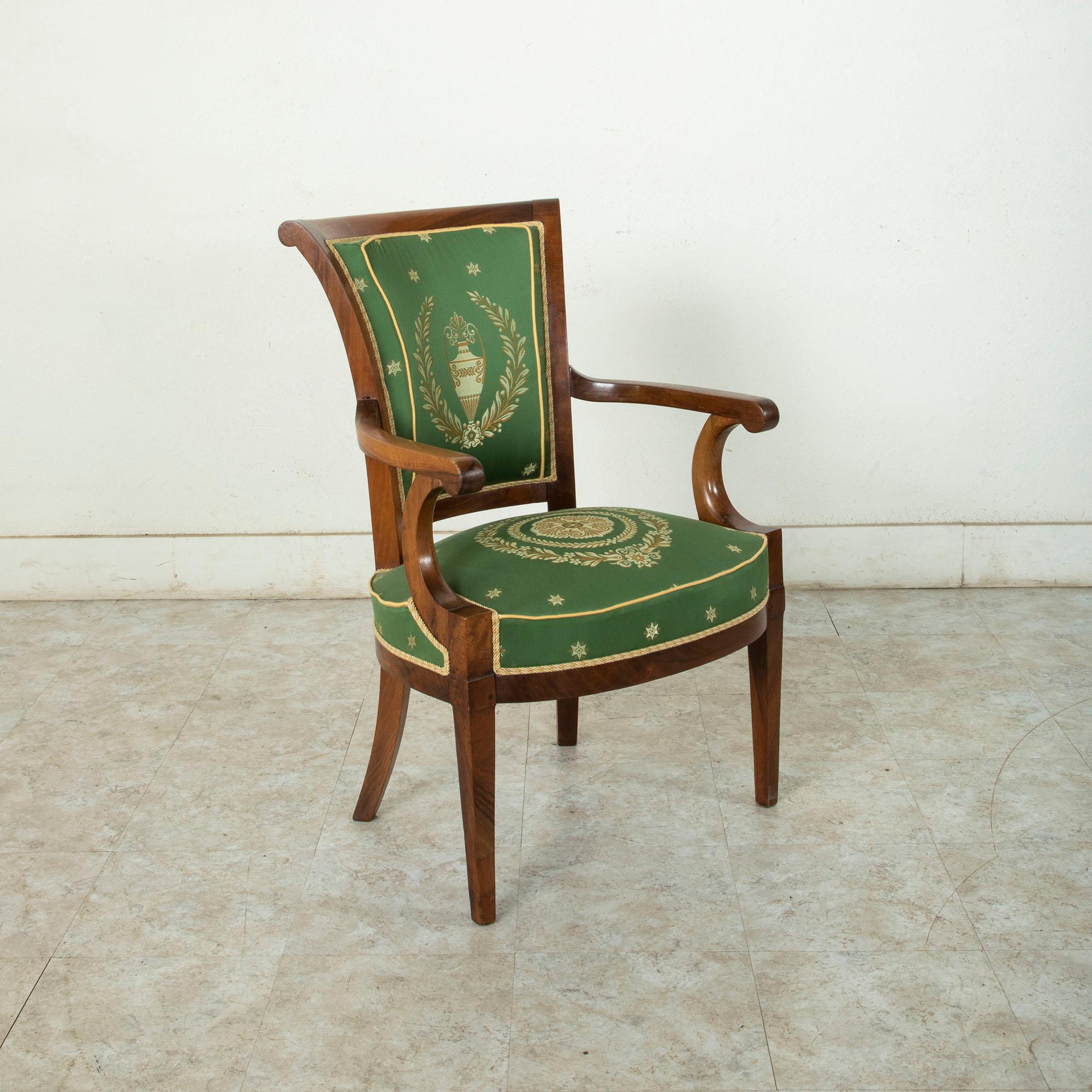 From a chateau in Normandy, France, this late 18th century Directoire period hand pegged mahogany armchair features green silk upholstery detailed with embroidered Directoire embellishments of laurels, stars, and an urn on the seat back. The seat