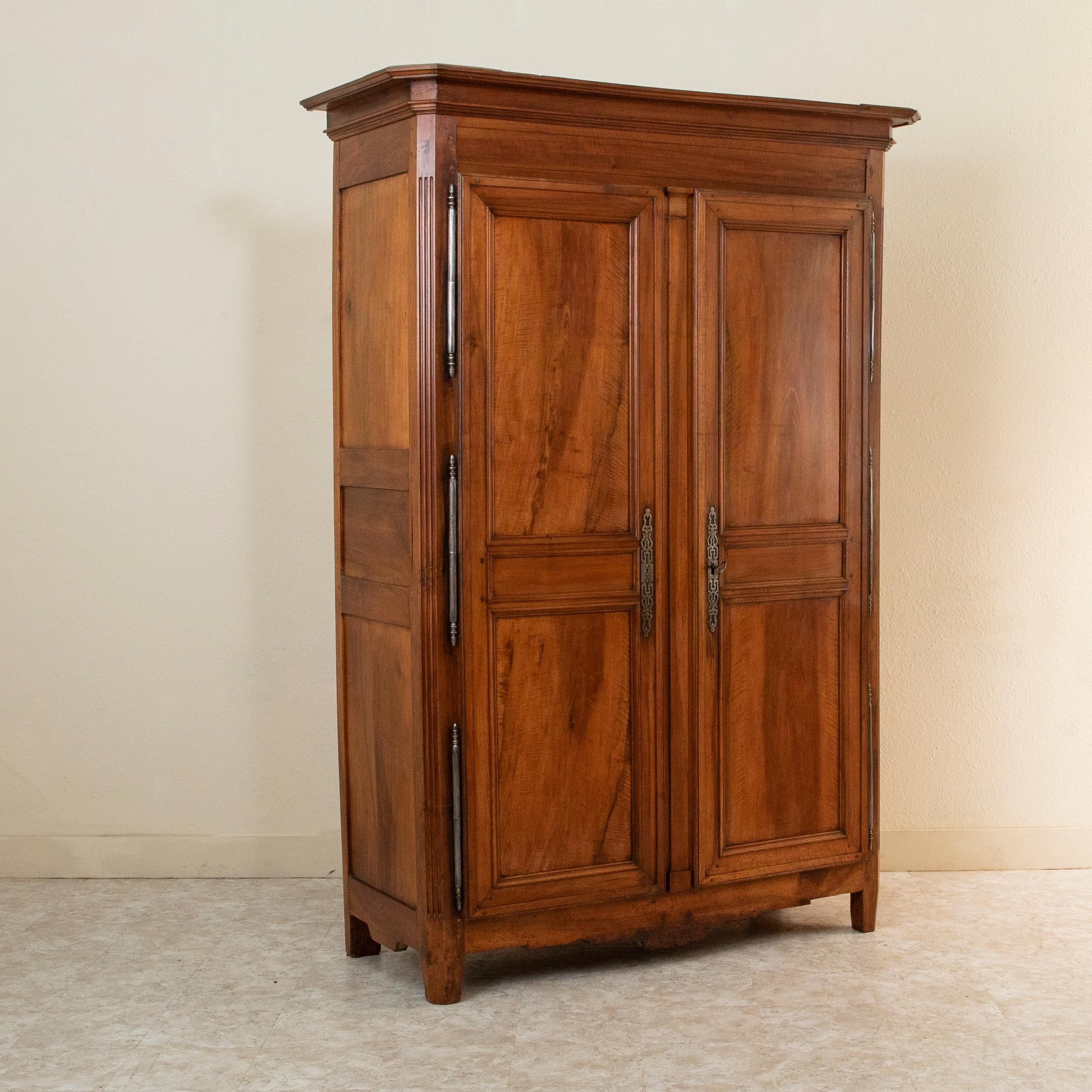 Standing at just over seven and a half feet in height, this late eighteenth century French Directoire period armoire is constructed of hand pegged paneled sides and doors of solid walnut. Found near the city of Bourges, France, this piece features