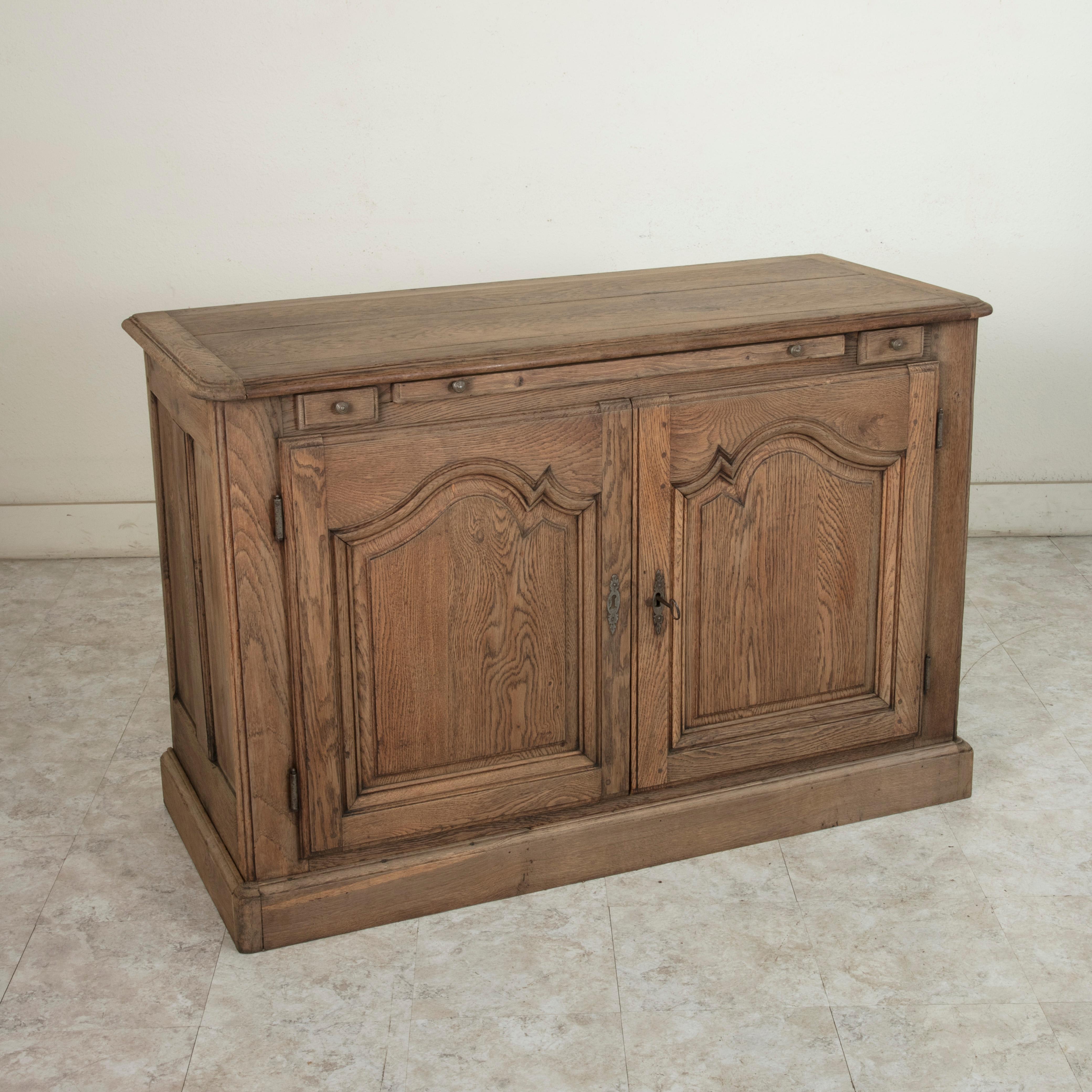 This 18th century French Louis XIV style oak hunt buffet features hand pegged solid paneled sides. Its beveled edge top rests above two drawers of dovetail construction originally used for storing carving knives. Between the drawers is a pull out