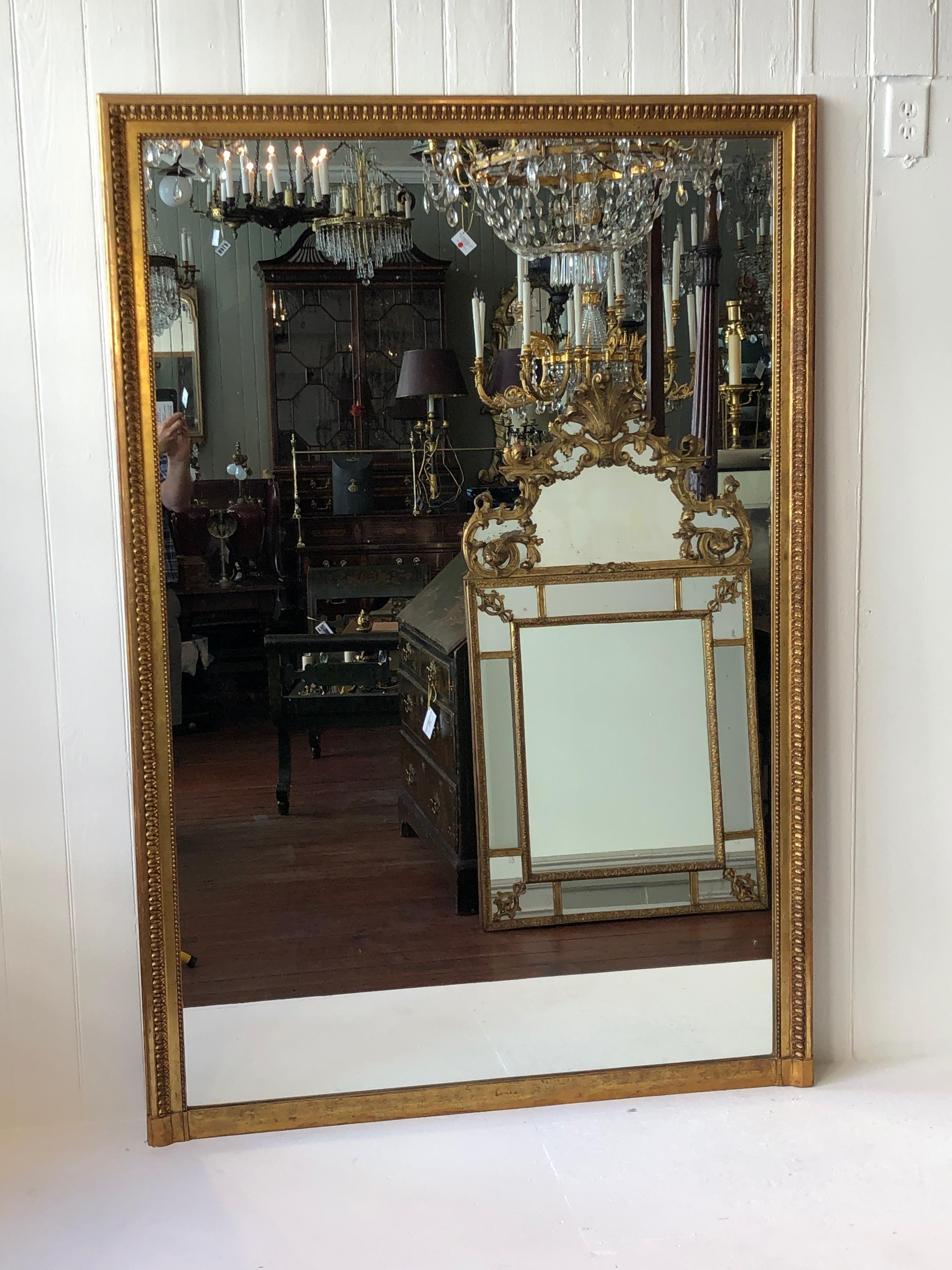 Late 18th century French, Louis XVI carved giltwood overmantle mirror. This elegant gilt carved mirror bears a simple frame with a garland of flat flowers around the perimeter with balls around the inner edges. This mirror would work nicely within