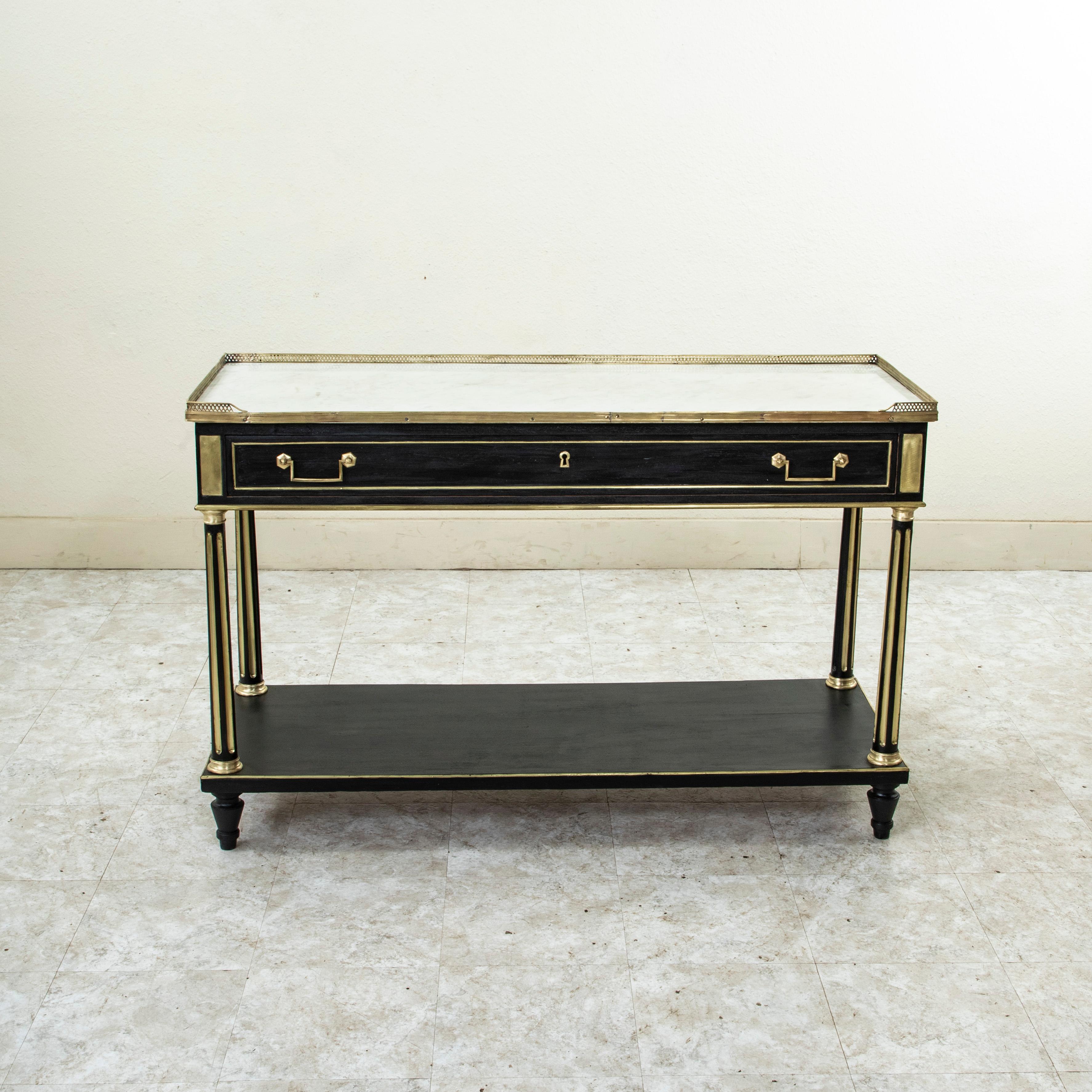This late eighteenth century French Louis XVI period black painted console table features a white marble top surrounded by a pierced bronze gallery. A long single drawer of dovetail construction fits into the apron below and is detailed with an