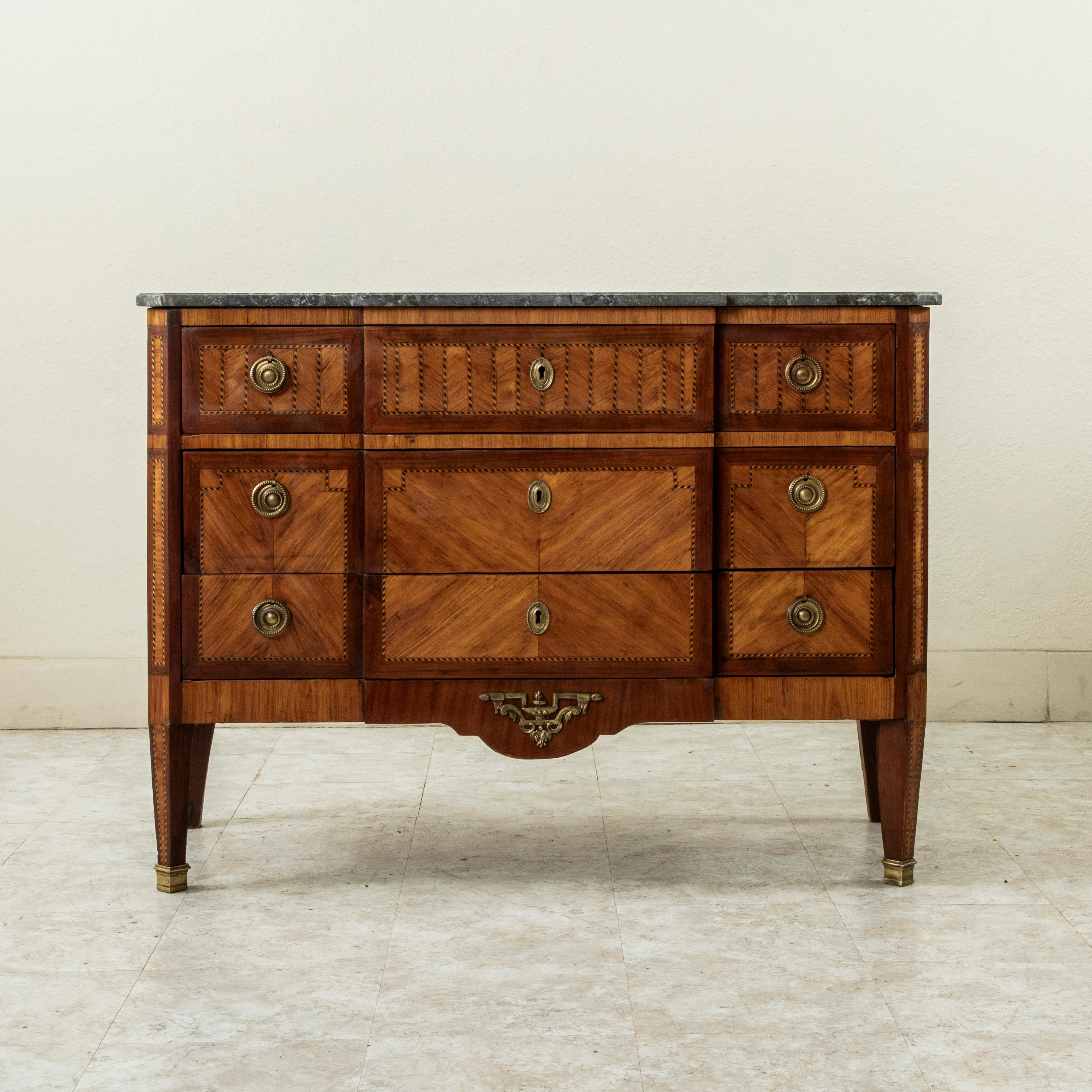 This smaller scale late 18th century French Louis XVI period chest features a beveled Saint Anne marble top and a geometric marquetry facade of rosewood, lemon wood, mahogany and ebonized pear wood. A marquetry gallery details the top drawer front
