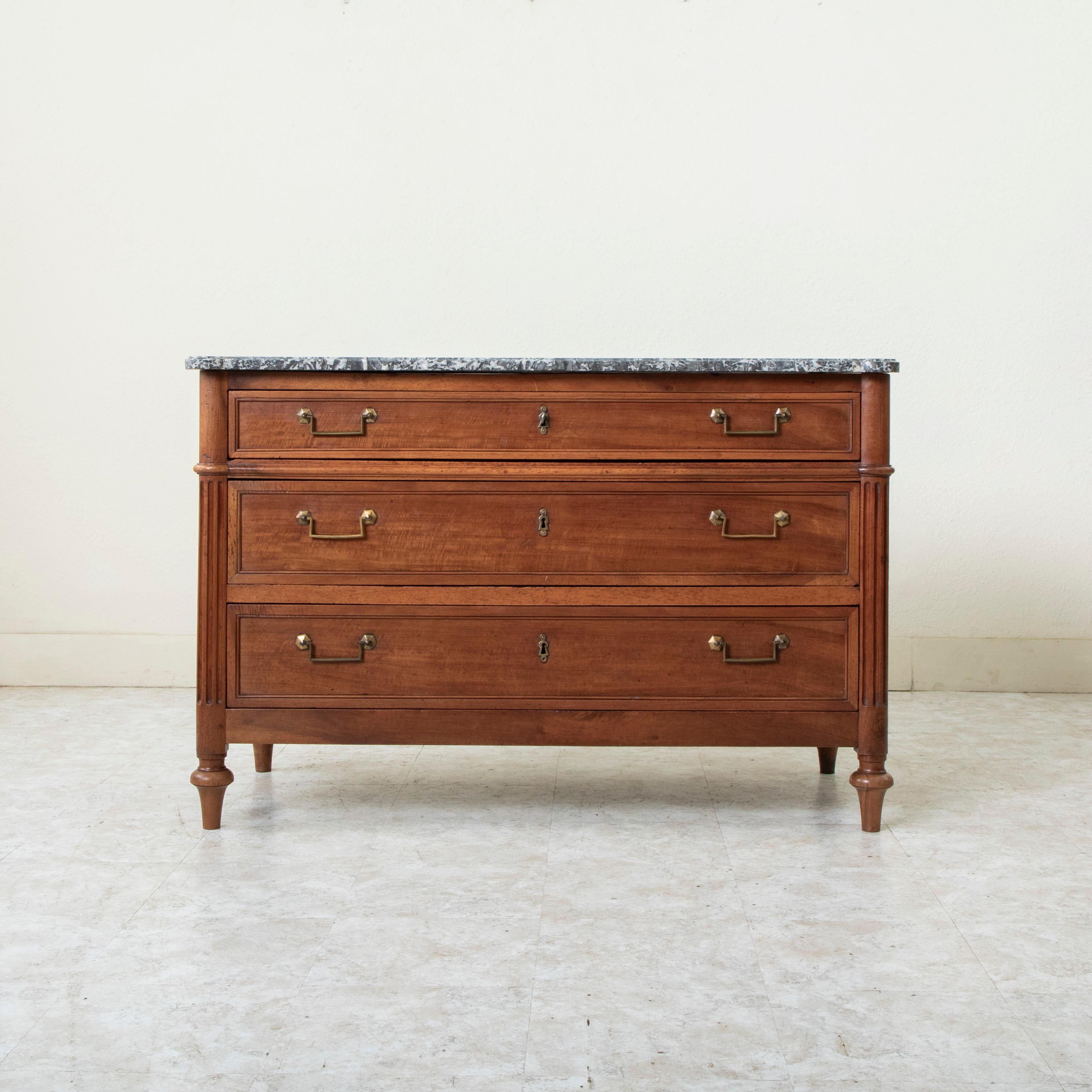 Questa commode o cassettiera in noce di epoca Saint Louis XVI, risalente alla fine del XVIII secolo, presenta il piano in marmo originale di Saint Anne. I tre cassetti con struttura a coda di rondine sono impreziositi dai classici tiretti con