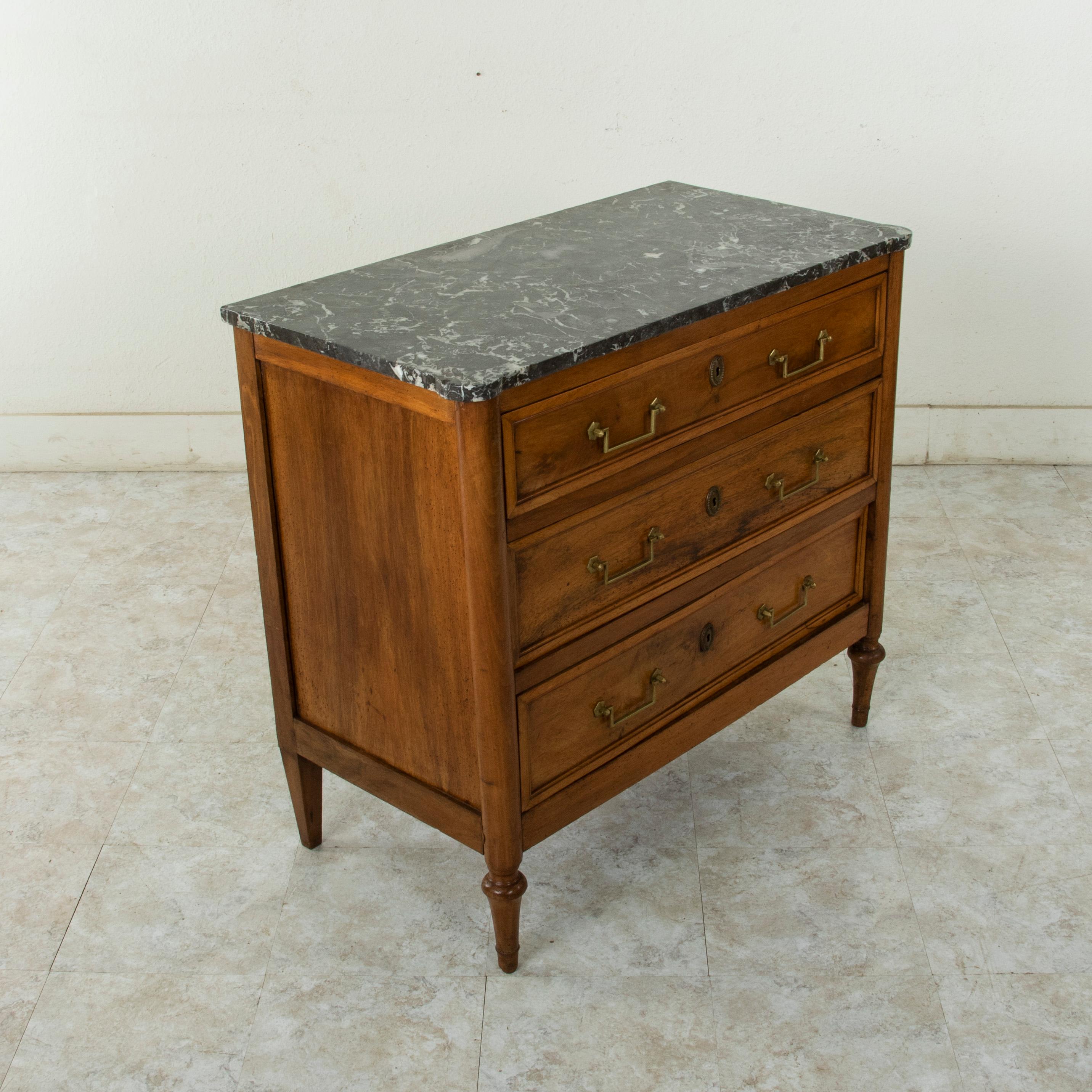 Unusual for its smaller size with a 37.25 inch width, this late 18th century French Louis XVI period commode or chest of drawers features its original Saint Anne marble top. Constructed of solid walnut, this piece has three drawers of dovetail