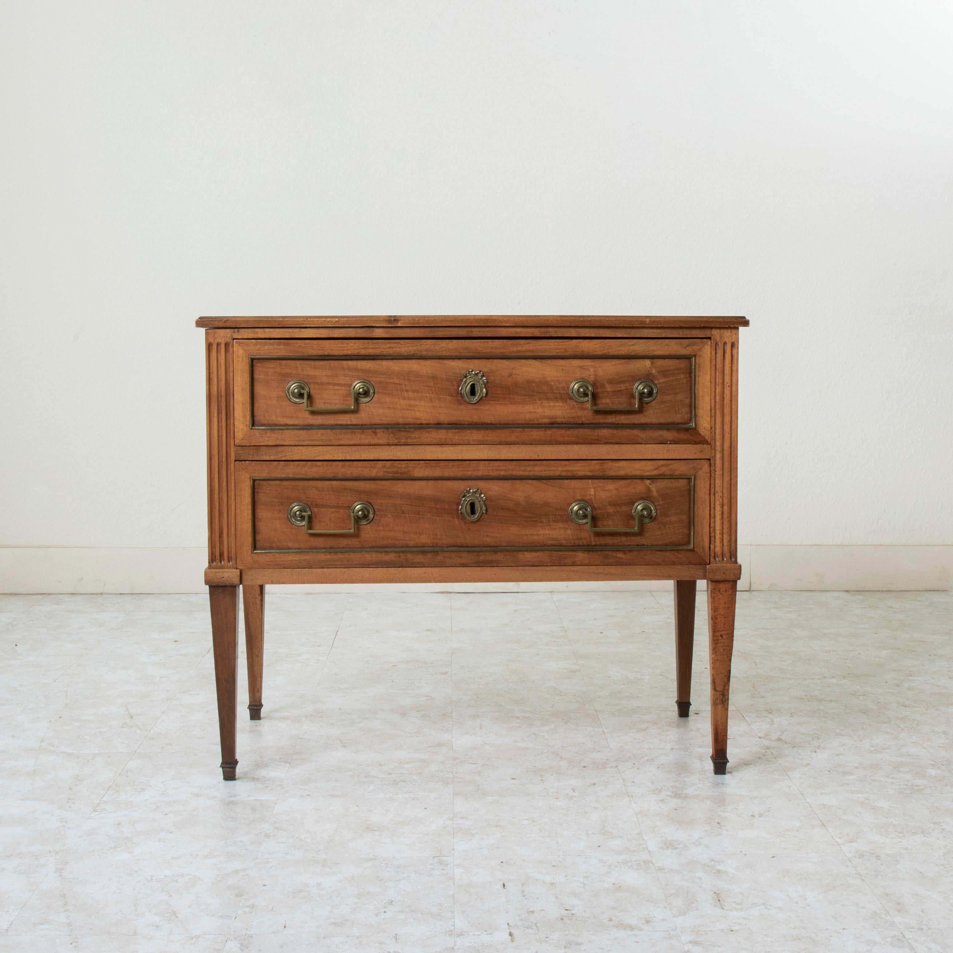 Questa piccola commode o cassettiera del periodo Luigi XVI, risalente alla fine del XVIII secolo, viene chiamata sauteuse in francese, o cassettone, per via delle sue gambe alte. Costruito in noce massiccio, questo mobile ha due cassetti a coda di