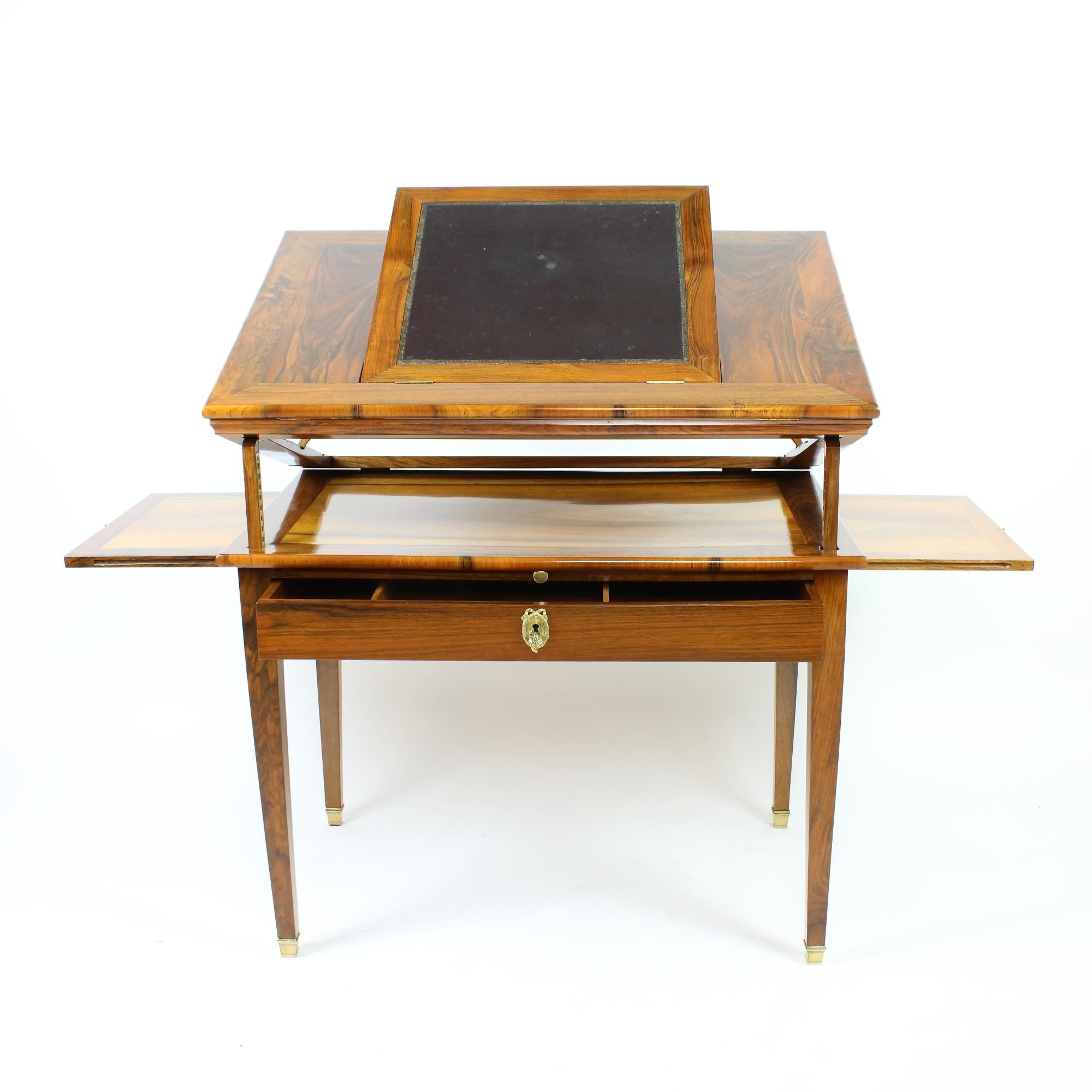 A late 18th century Louis XVI walnut architect's or mechanical table with a double-hinged ratcheted top comprising an original gold-tooled black leather lined writing plate, which can be changed in position, veneered in walnut of beautiful warm