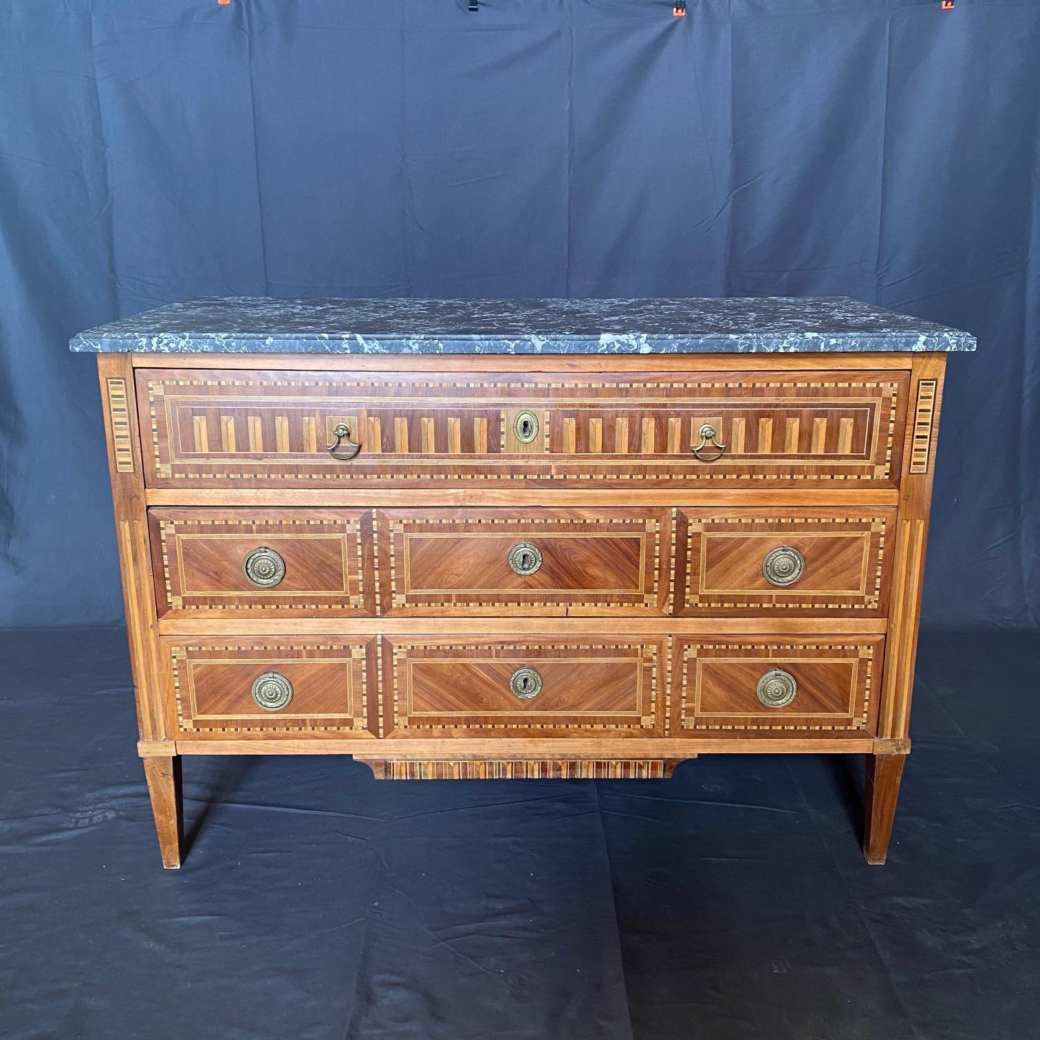 A fine late 18th Century French inlaid walnut commode, dresser or large chest of drawers, having high Louis XVI neoclassical form, three spacious drawers, separated by a moulding that runs around the front of the piece. Bronze wreathed pulls and