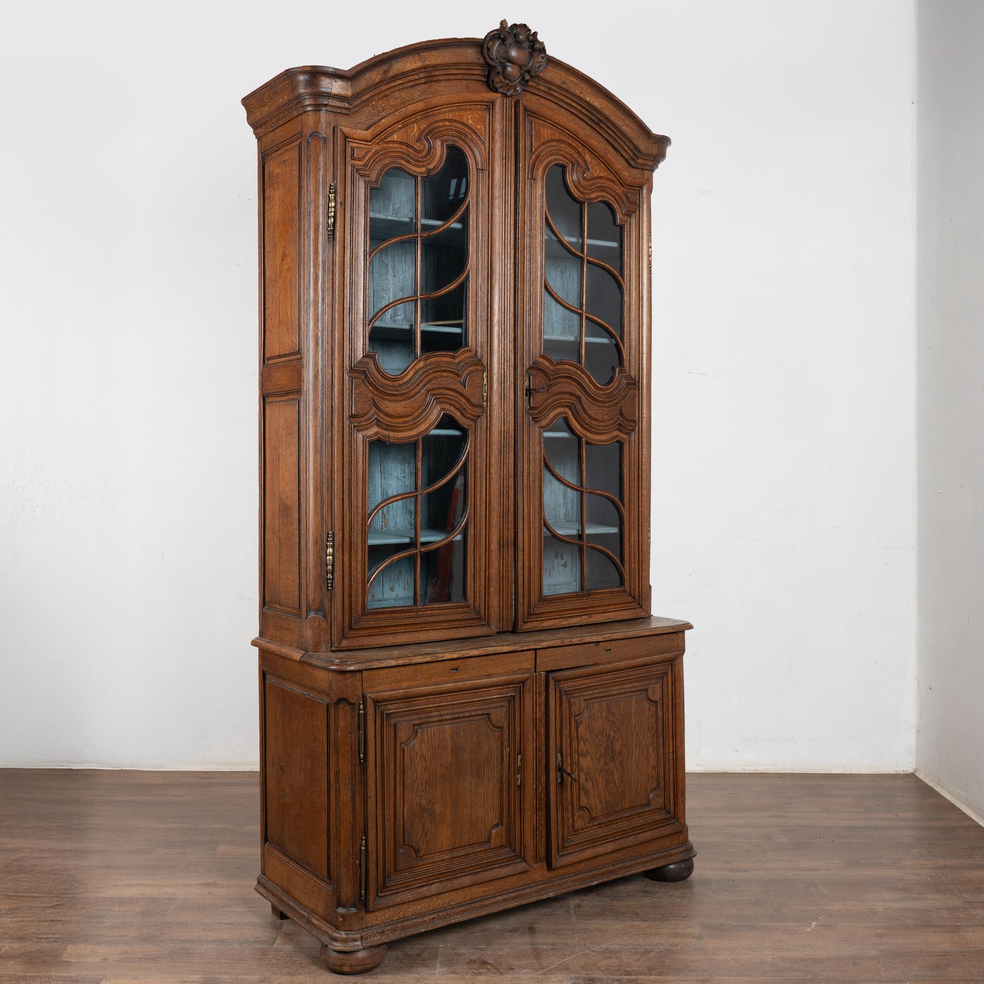 Grande armoire Deux-Corps en chêne de style provincial français de la fin du XVIIIe siècle ou du début du XIXe siècle.
Les vitres supérieures et les portes de l'armoire à panneaux inférieurs sont sculptées et ornées de volutes. Deux tiroirs
