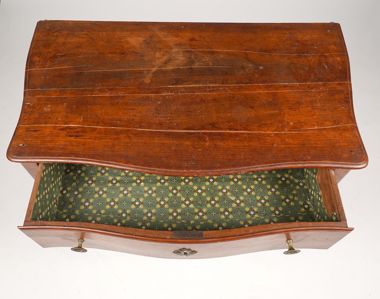 Dating to the late 18th century this French Provincial Cherry commode features serpentine front and sides, one deep drawer, carved shaped aprons and cabriole legs with stylized hoof feet. The cherry wood has through centuries obtained an attractive