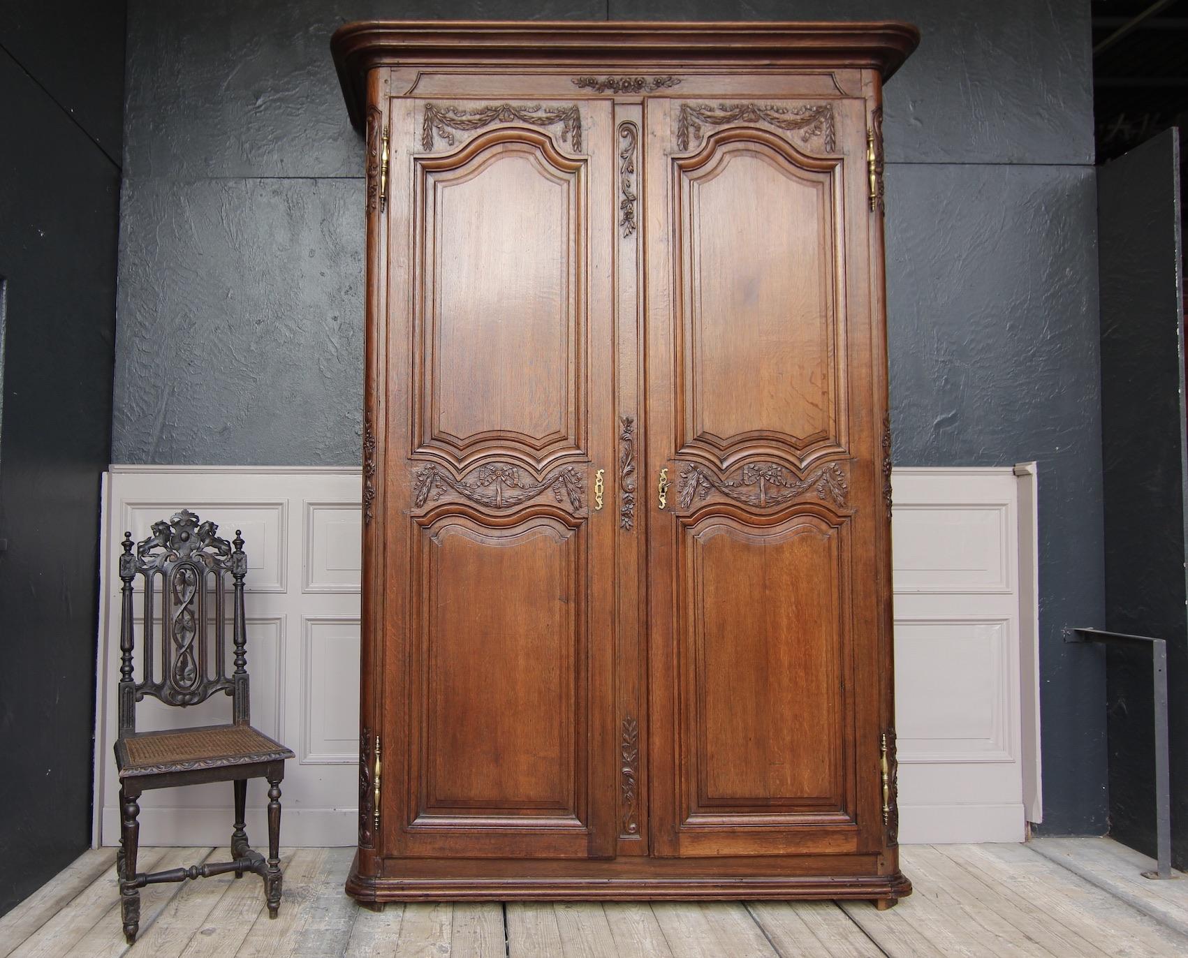 Large late 18th-century Louis XVI style armoire or cabinet from France. Made of solid oak and waxed. Circa from the end of the 18th century.
Body, with rounded corners, partially carved. Tall doors on large hand-made external brass fittings.
2