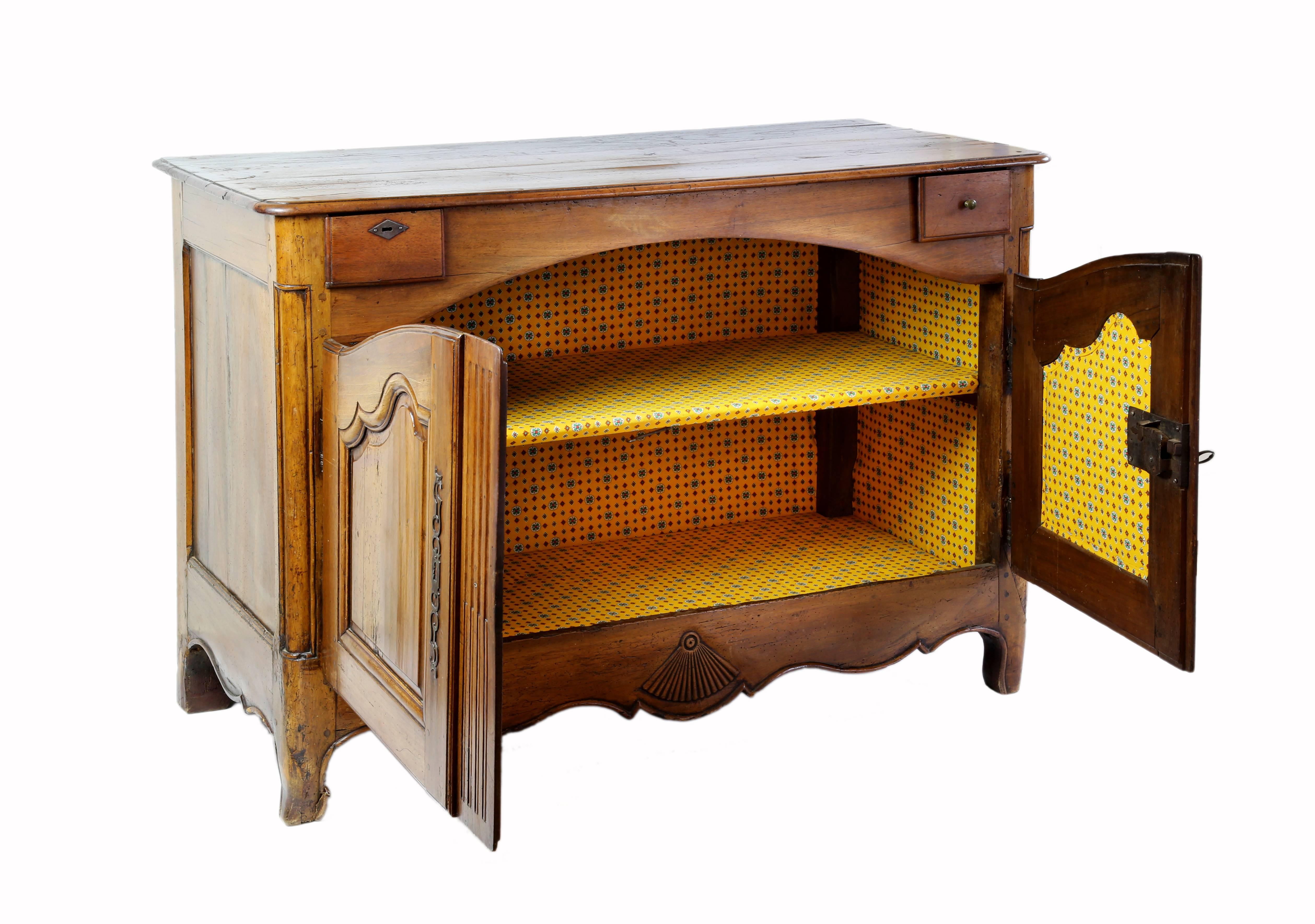 Walnut sideboard or buffet. The case is fitted with two small drawers over double-door cabinet opening to shelves. The apron is scalloped with a central carved fan motif.