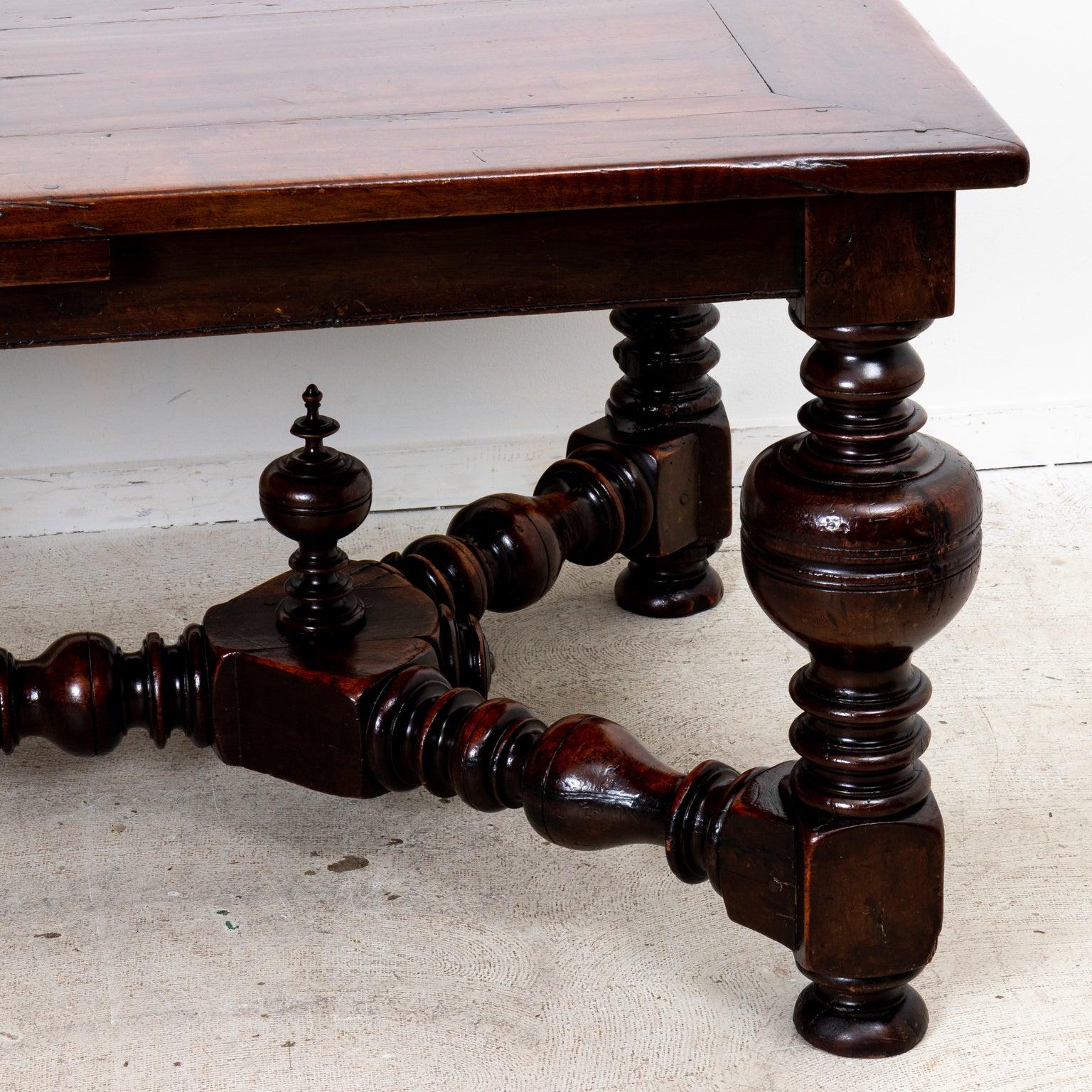 This late 18th century French walnut table exhibits a time warn patina, with dramatic bulbous turned legs and stretcher bar featuring turned finials and bun feet. Two sets of extension leaves included. Measures: 24.5