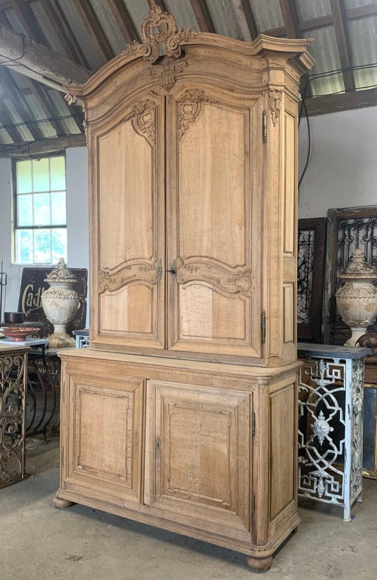 A beautiful late 18th century French cupboard in washed oak. Made in 2 parts it has lovely quality wood carvings and decorative mouldings. The oak has been bleached to give it an appealing lighter colour.  With 2 original working iron keys.