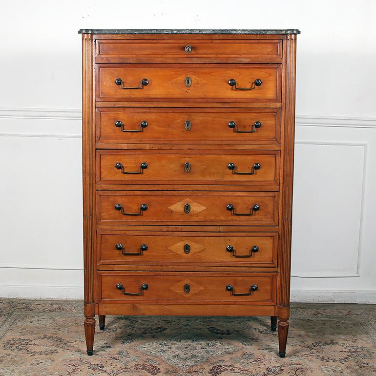 A handsome late 18th century French semainier or tall chest in fruitwood, featuring a marble top over seven drawers (one for each day of the week!) between opposing fluted columns and paneled sides. Each drawer with a beaded frame and original brass