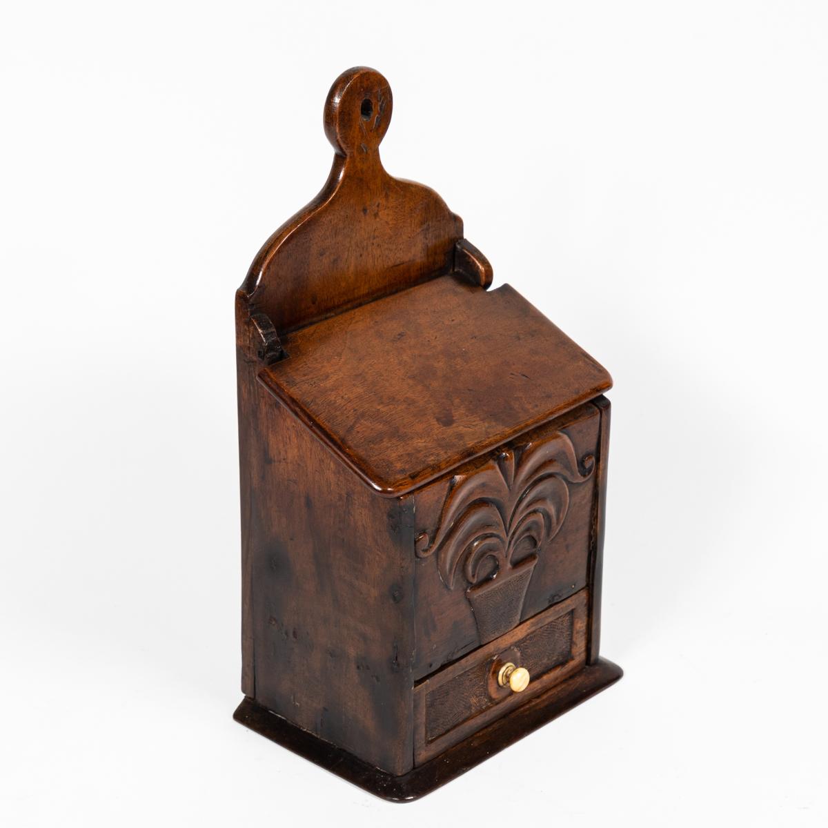 English late 18th-century fruitwood spice box, featuring a small drawer at its base with a carved ivory knob. The figurative carving of a plant on the box's front speaks to piece's original function. Due to its notched handle support, the box can be